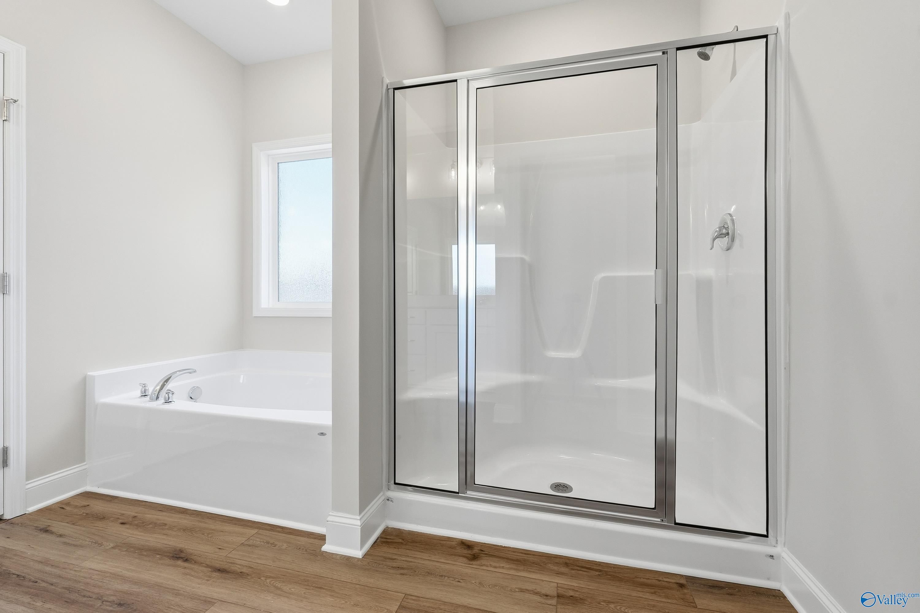 Modern master bathroom featuring freestanding tub and glass shower enclosure in The Everett, Davidson Homes, Harvest, Alabama