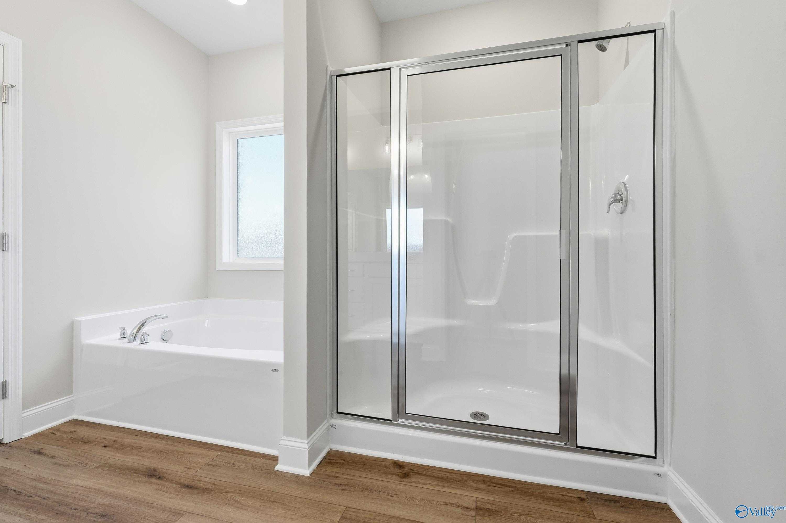 Modern master bathroom featuring freestanding tub and glass shower enclosure in The Everett, Davidson Homes, Harvest, Alabama