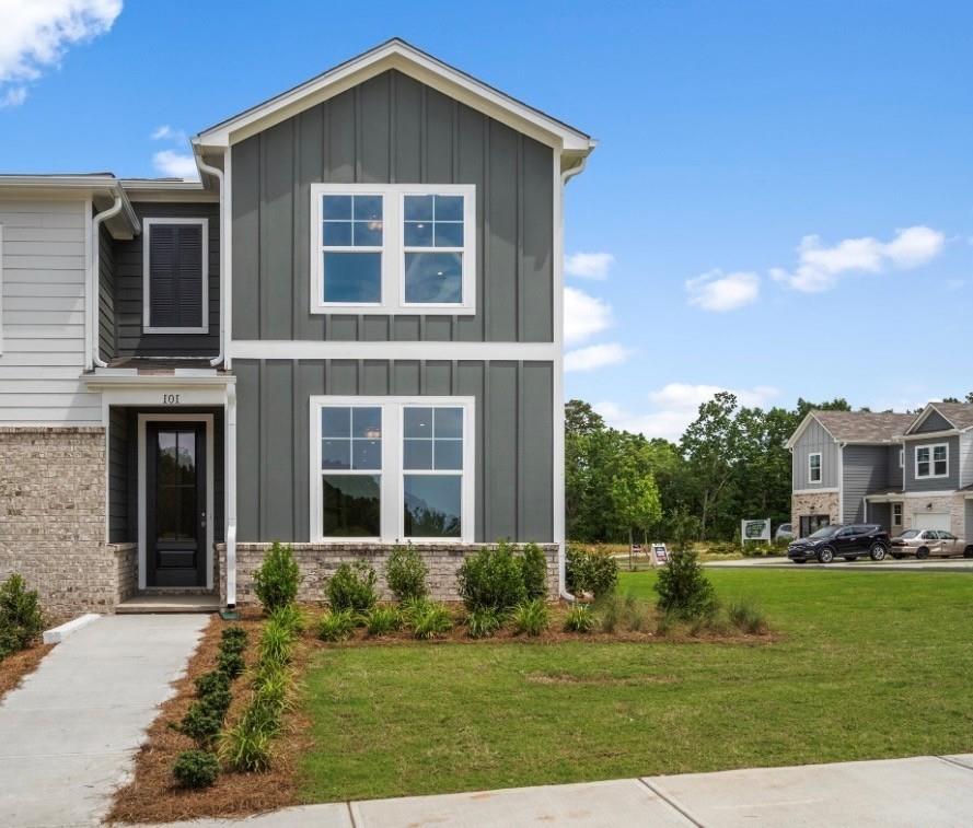 Two-story gray board-and-batten home with brick base, black front door, and landscaped yard in Stegall Village, Emerson, Georgia