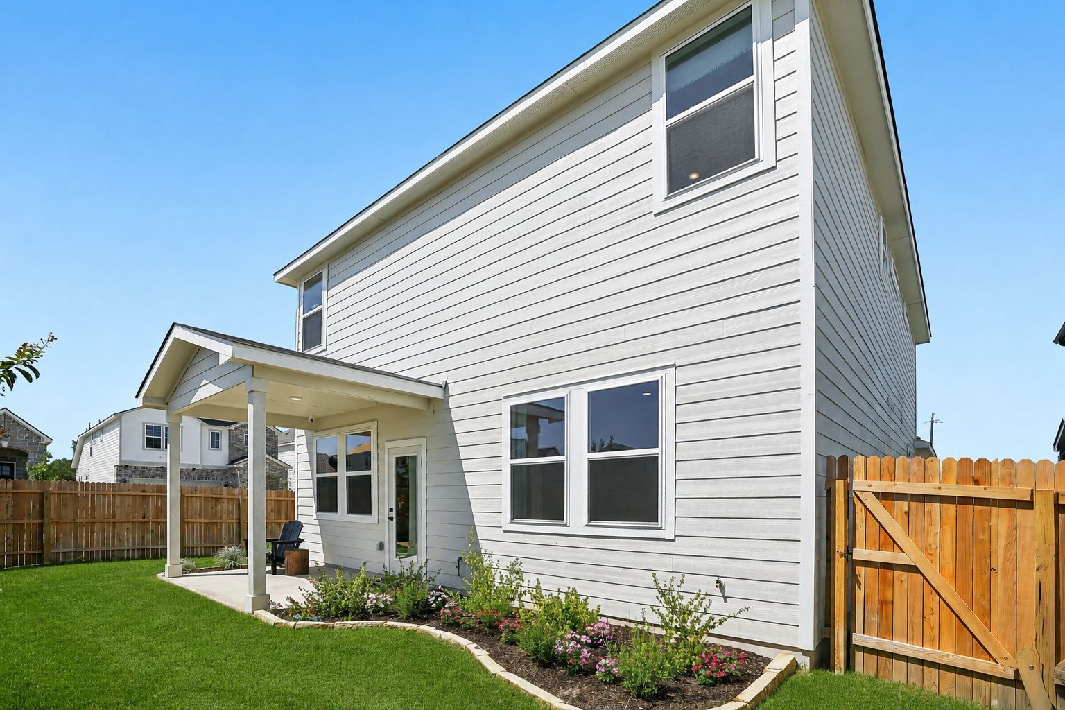 Backyard view of a Davidson Homes house at Fairway Crossing in Converse, Texas, featuring a covered patio and wood fence.
