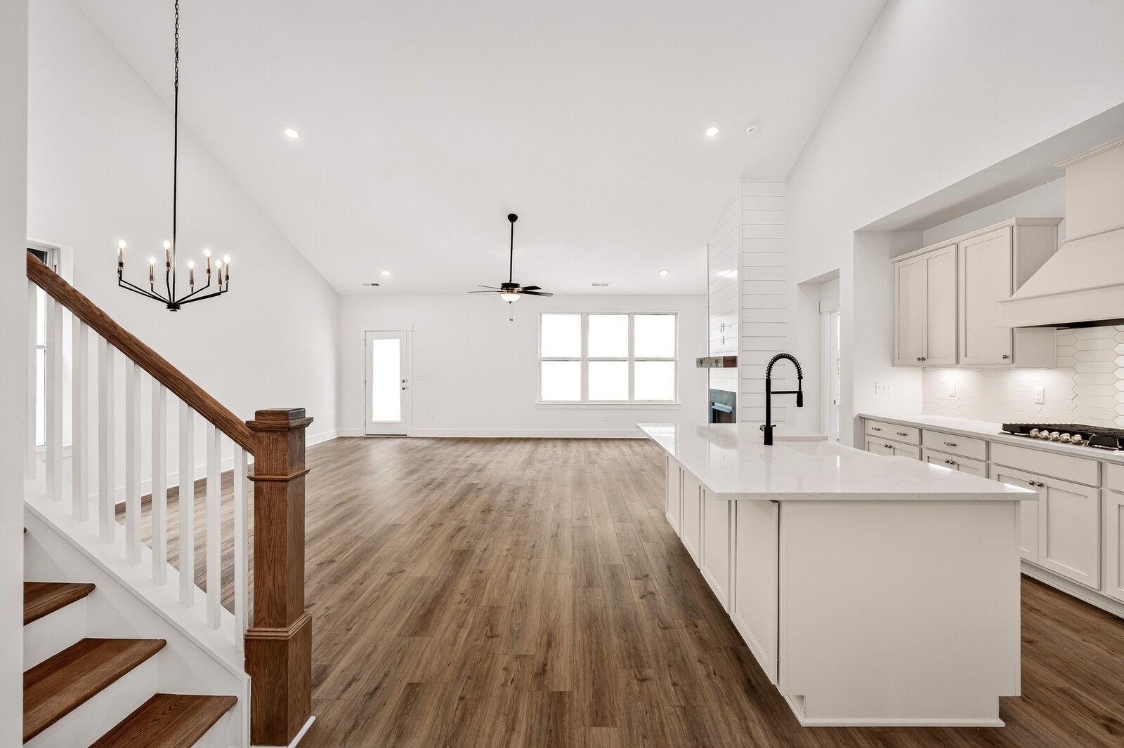 Bright open-concept kitchen-living area with white quartz island, hardwood floors, wooden staircase in Davidson Homes Ridgeport C, Gallatin TN