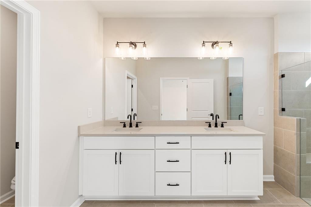 Modern master bathroom with double vanity, white shaker cabinets, and glass shower in Davidson Homes The Glenwood A, Loganville, GA