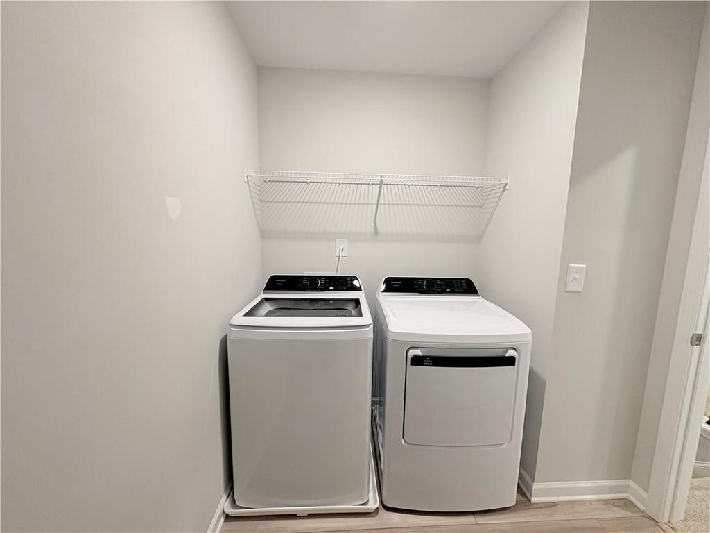 Modern laundry room featuring white washer, dryer, and wire shelving in Davidson Homes The Wake E, Cumming, Georgia