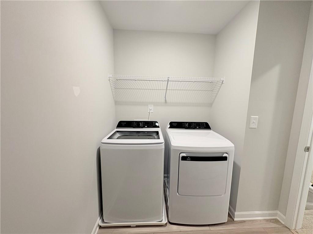 Modern laundry room featuring white washer, dryer, and wire shelving in Davidson Homes The Wake E, Cumming, Georgia
