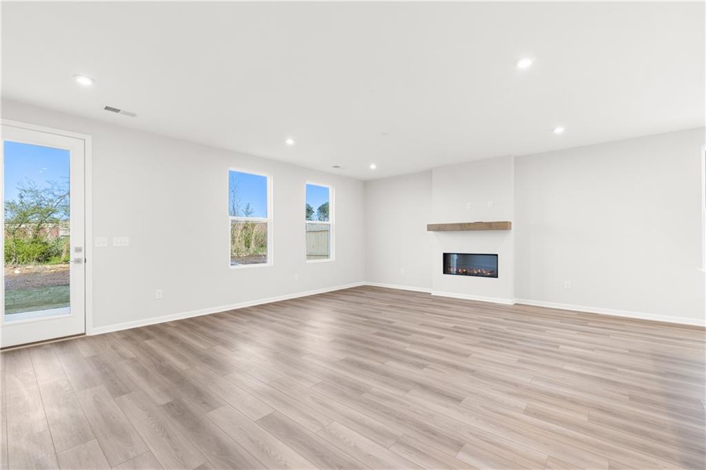 Bright living room with gas fireplace, luxury vinyl plank floors, large windows and sliding door to backyard in Davidson Homes Cary A, Winder GA