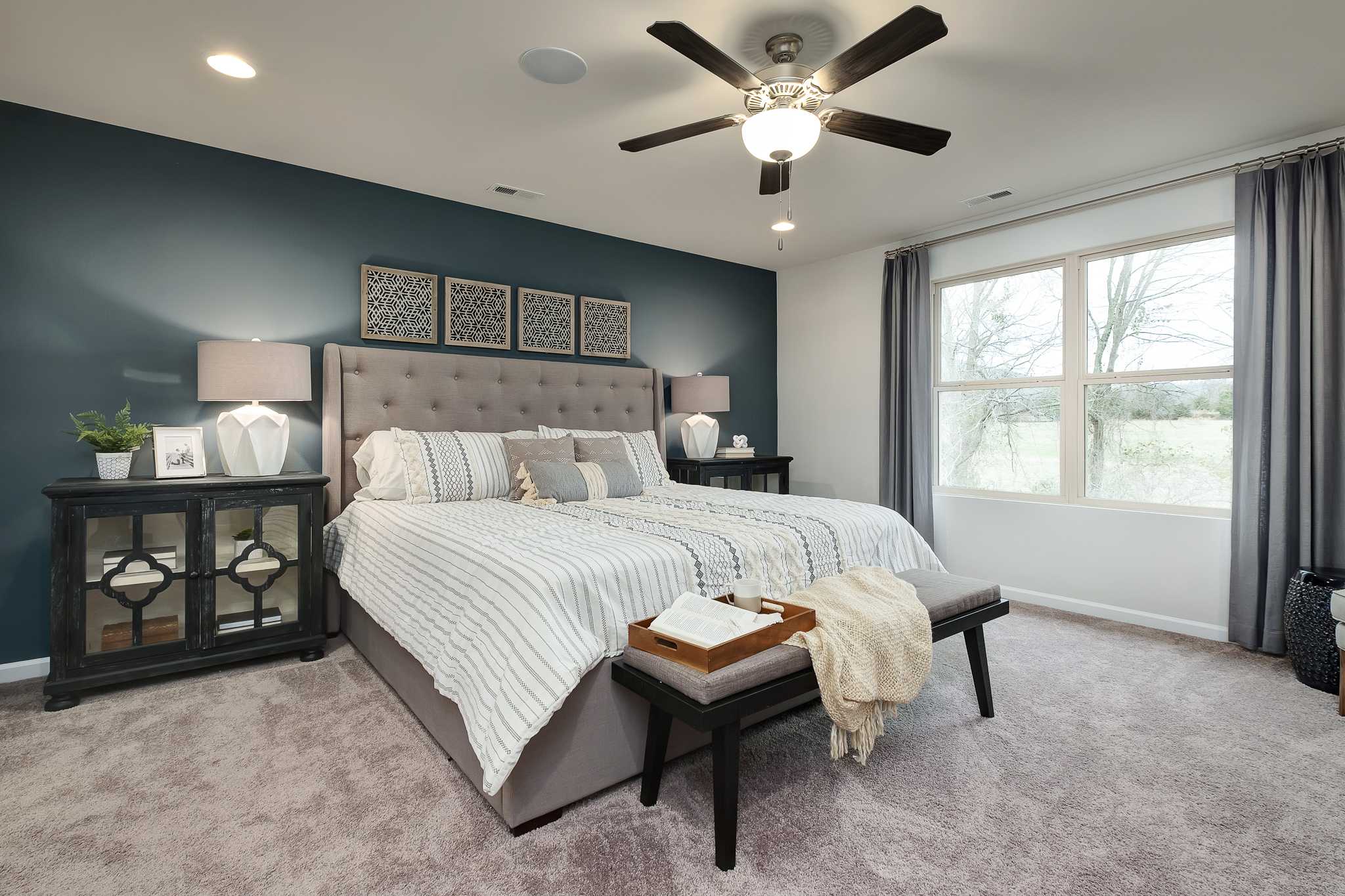 Spacious master bedroom at The Reserve at Overton in Hampton Cove Alabama with king bed, navy accent wall, ceiling fan
