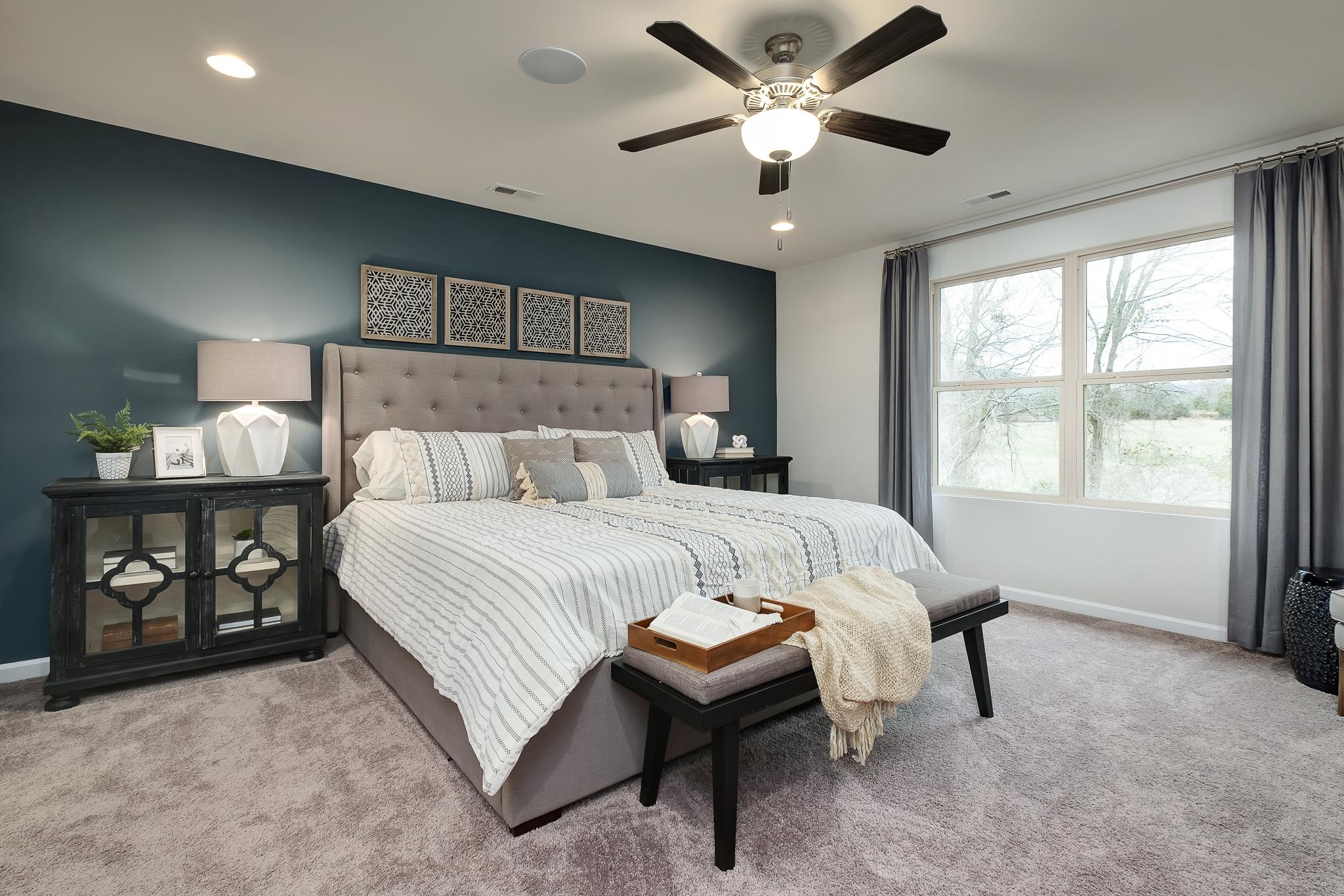 Spacious master bedroom at The Reserve at Overton in Hampton Cove Alabama with king bed, navy accent wall, ceiling fan