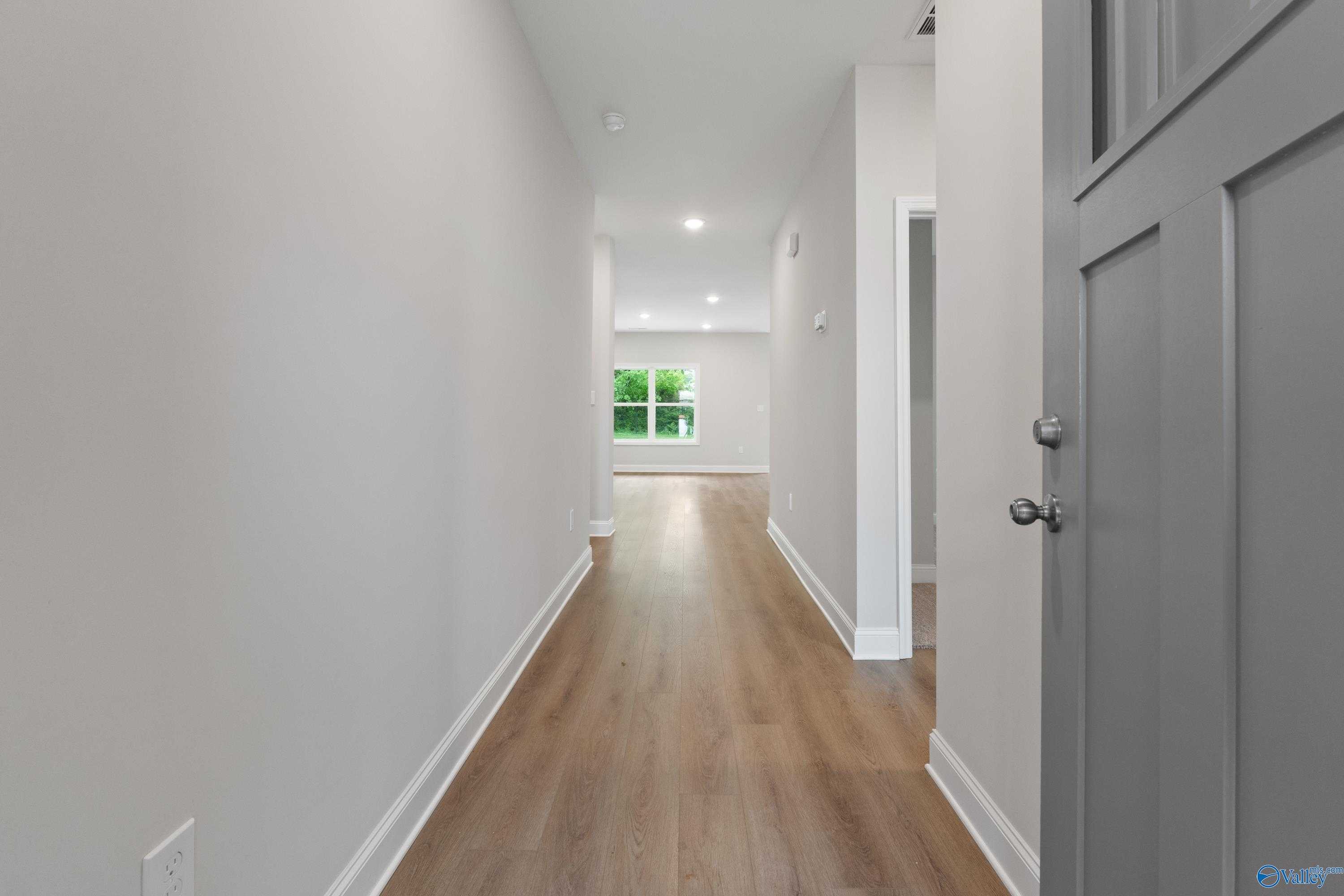 Bright hallway with hardwood floors, gray walls, and window view in Davidson Homes The Asheville C, Huntsville, Alabama