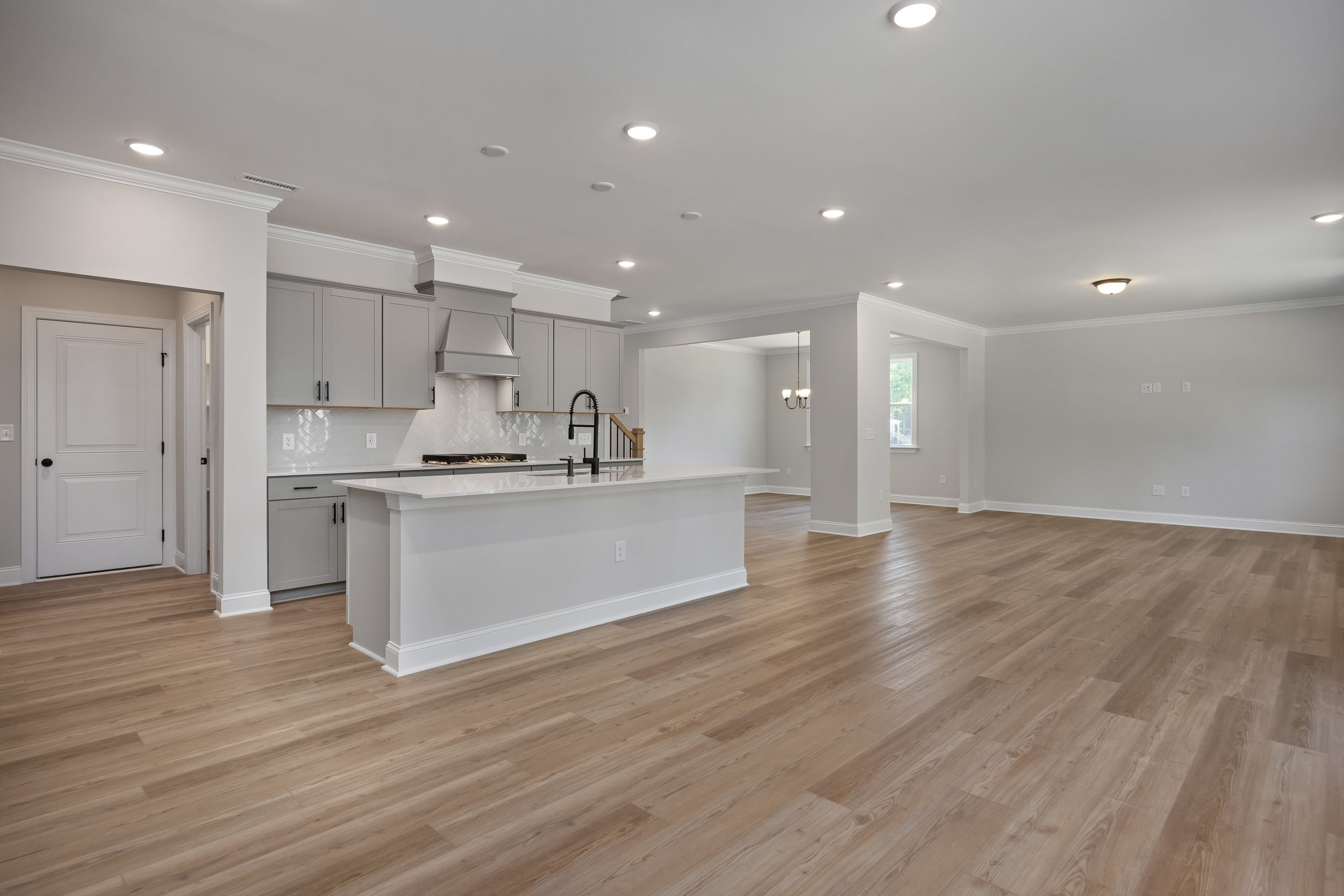 Spacious open-concept kitchen in Beech A home by Davidson Homes featuring white island, gray cabinets, and hardwood floors