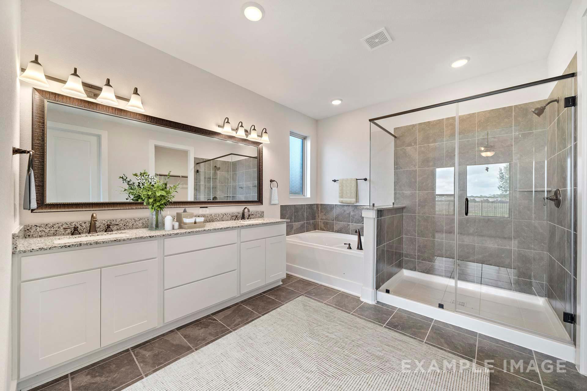 Spacious master bathroom in The Victoria A with double vanity, freestanding tub, and glass-enclosed shower