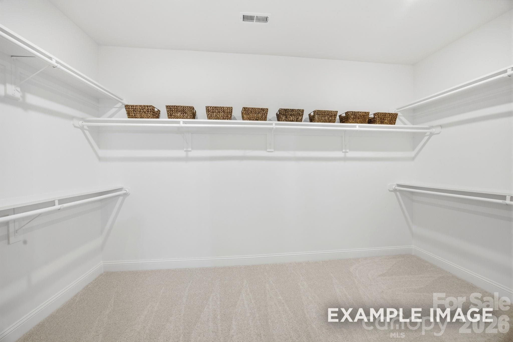 Spacious walk-in closet with white shelving, hanging rods, and wicker baskets in Davidson Homes Hickory C II, Belmont, NC