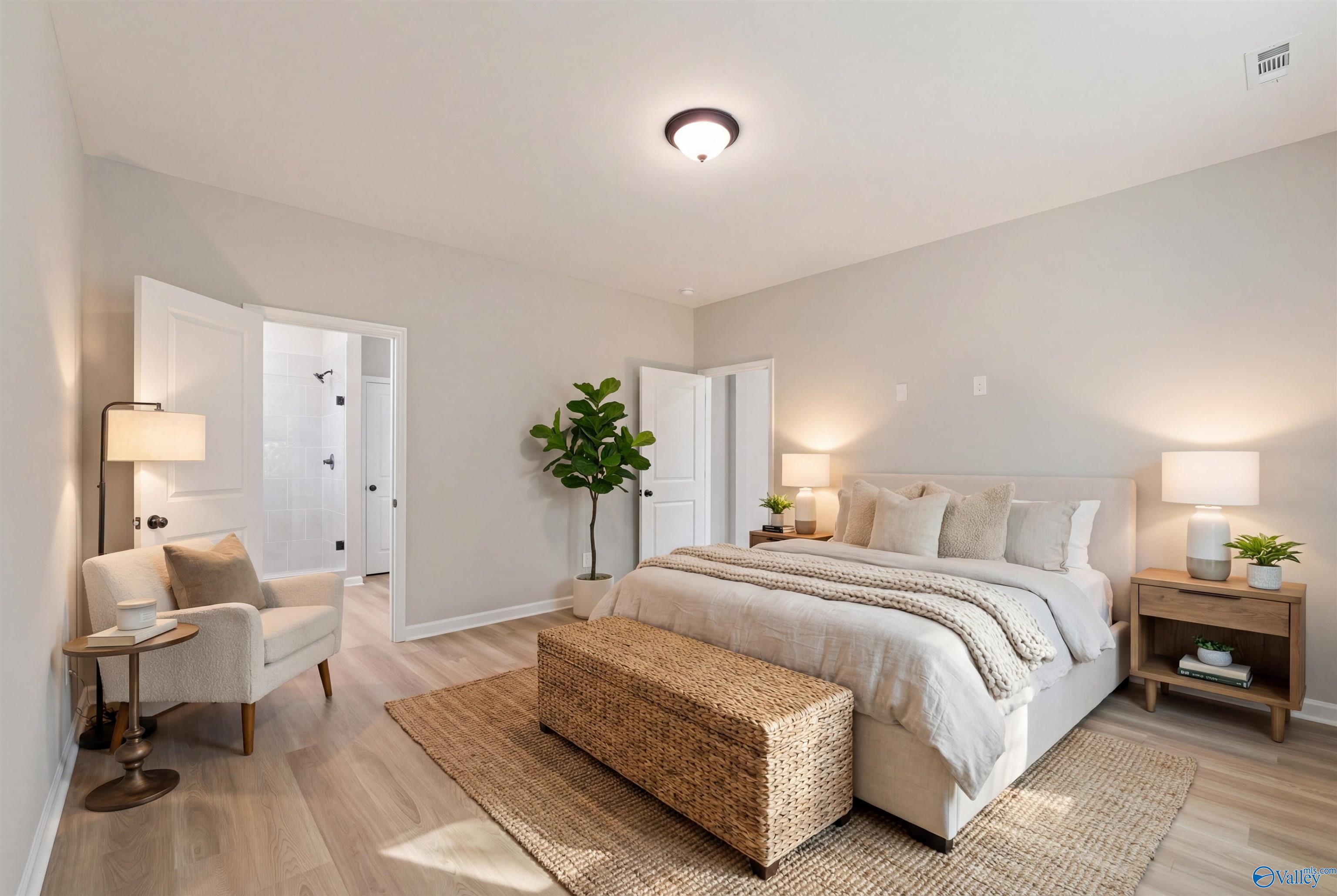 Elegant master bedroom with king bed, neutral tones, en-suite bath, and armchair in Davidson Homes The Phoenix, Hazel Green, AL