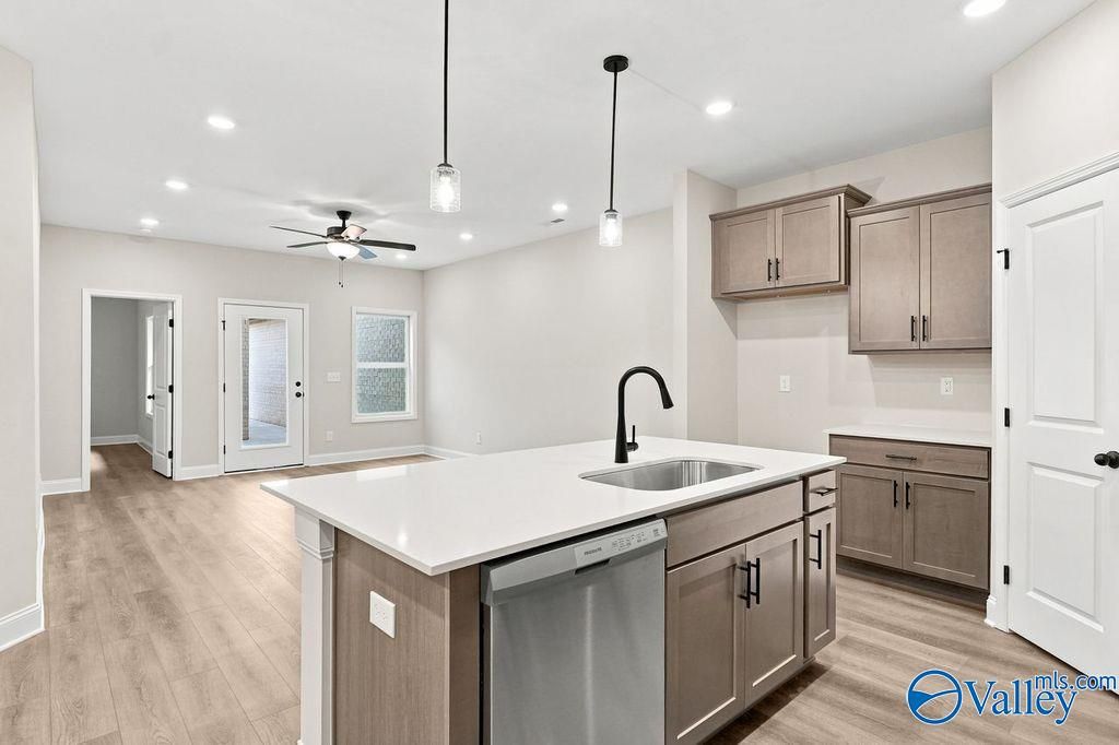 Modern kitchen with white island, granite countertops, and wood cabinets in The Camilla C floor plan, Hartselle, Alabama.