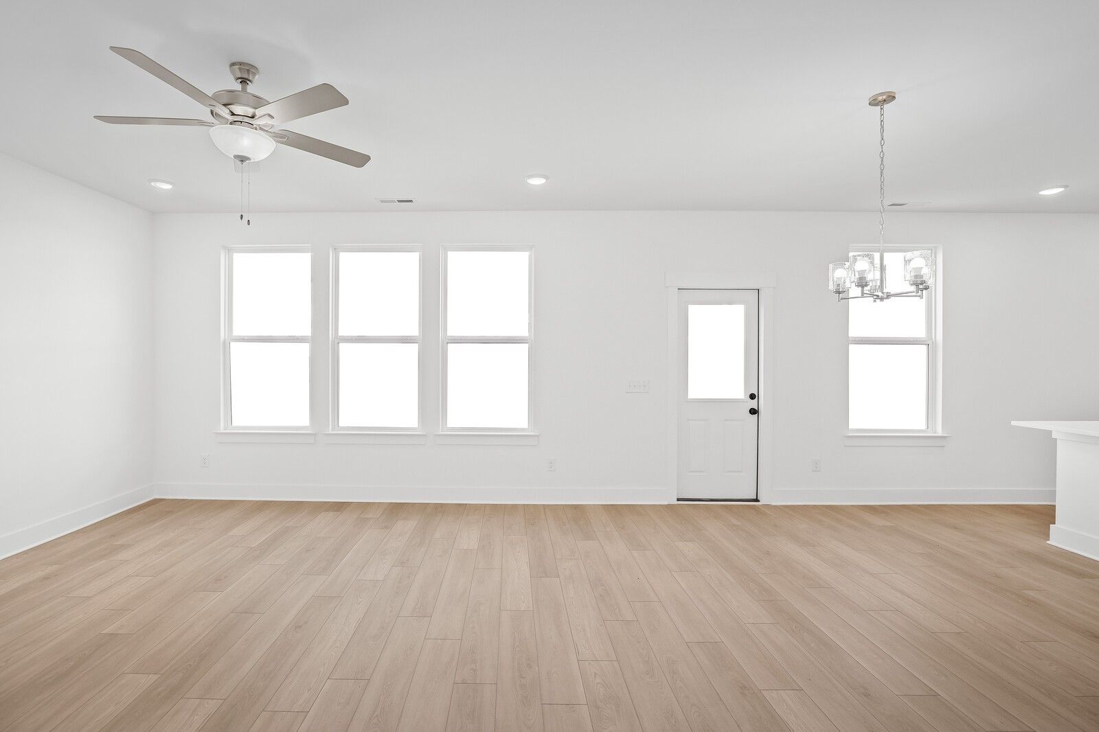 Bright open living room with hardwood floors, large windows, ceiling fan, and chandelier in The Logan C 3-bedroom home, Gallatin, TN