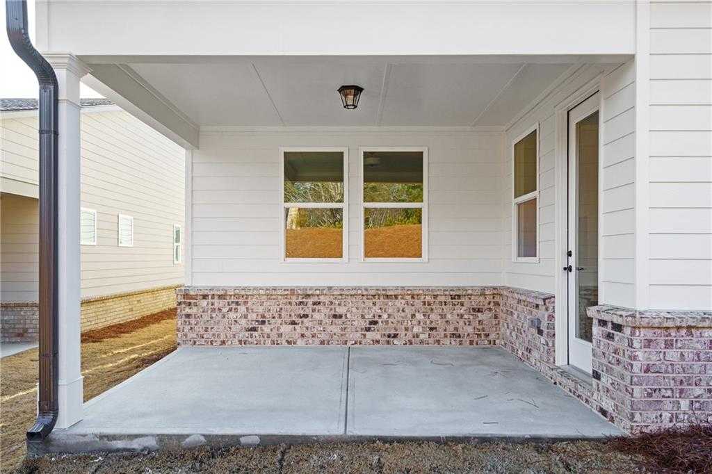 Covered back patio with brick accents, large windows, and concrete flooring in Davidson Homes The Edison A, Kelly Preserve, Loganville, GA