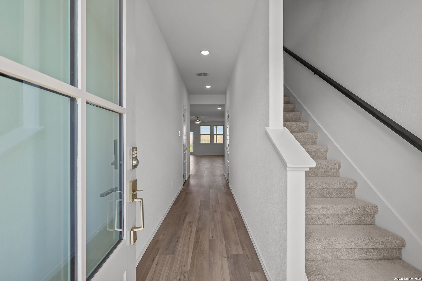 Bright entryway with wood-look flooring and carpeted staircase in The Brazos B floor plan by Davidson Homes in San Antonio.