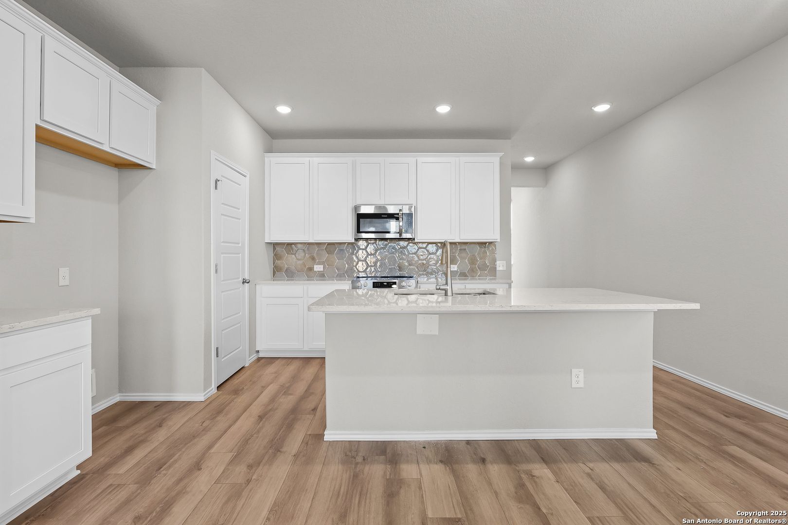 Modern white kitchen with quartz island, stainless appliances, and subway tile backsplash in Davidson Homes The Colorado B, San Antonio
