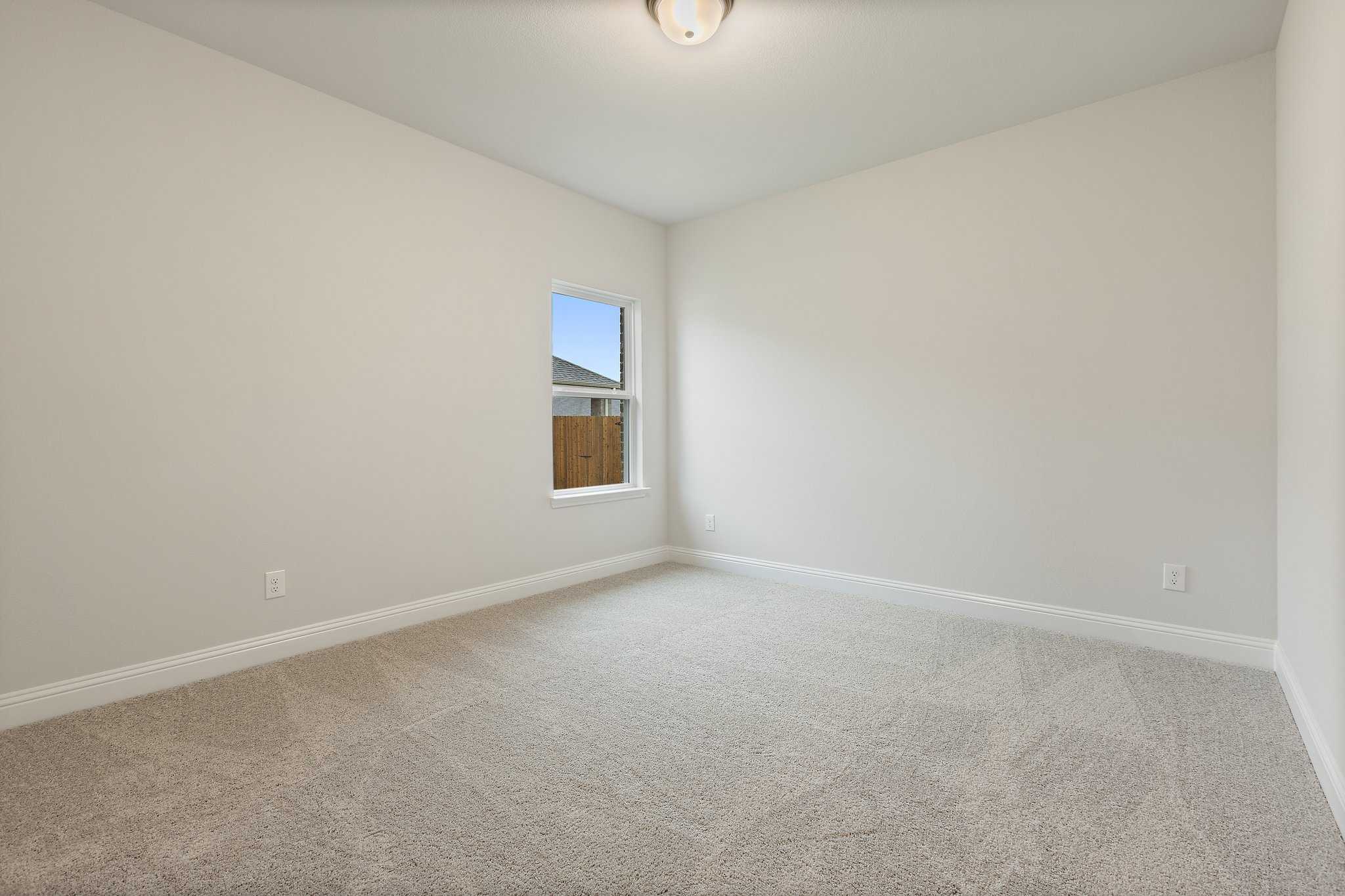 Spacious empty bedroom in The Harrison C with neutral beige walls, berber carpet, large window, and ceiling light