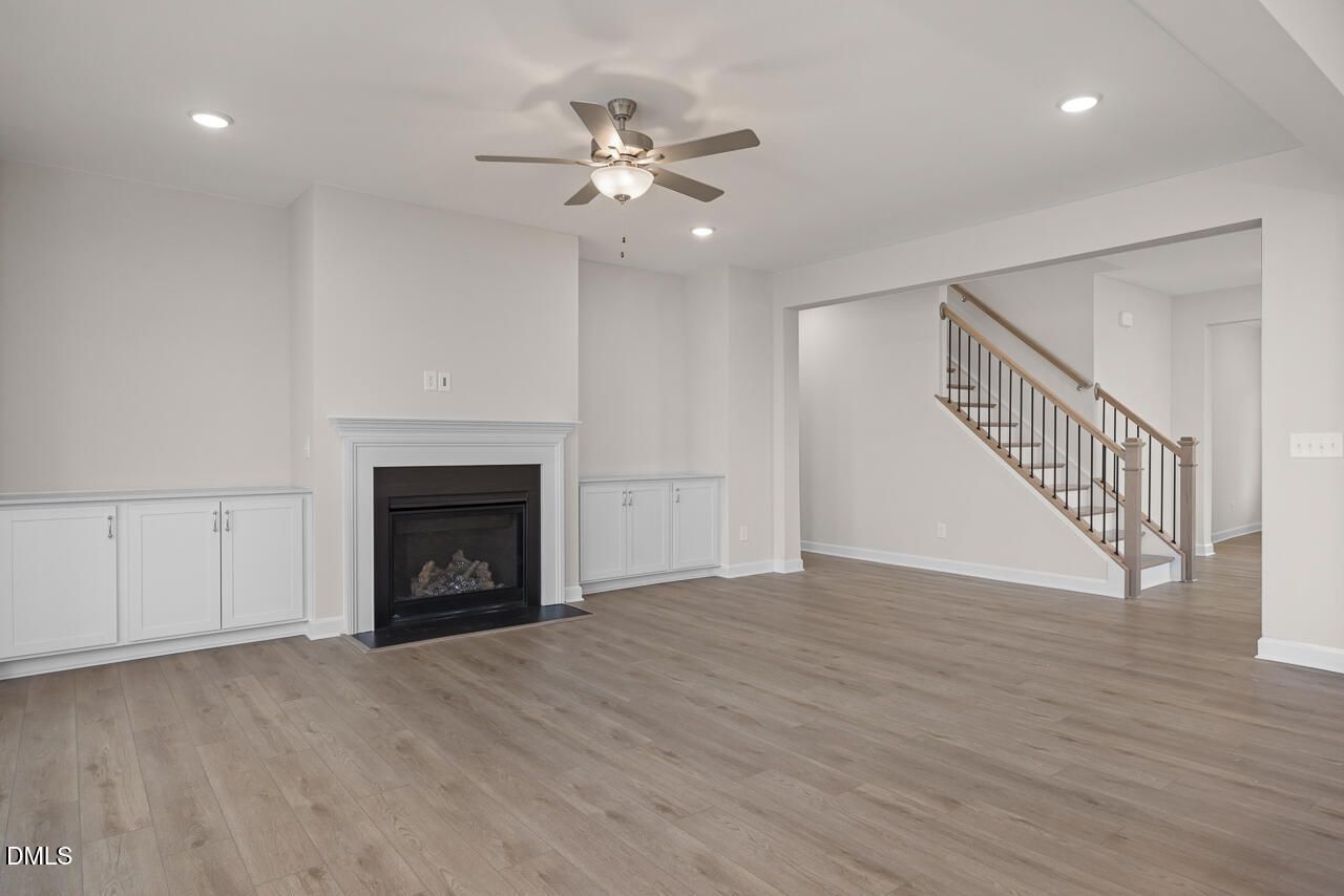 Cozy family room featuring gas fireplace, built-in cabinets, and hardwood floors in Davidson Homes The Cypress D II, Angier, NC