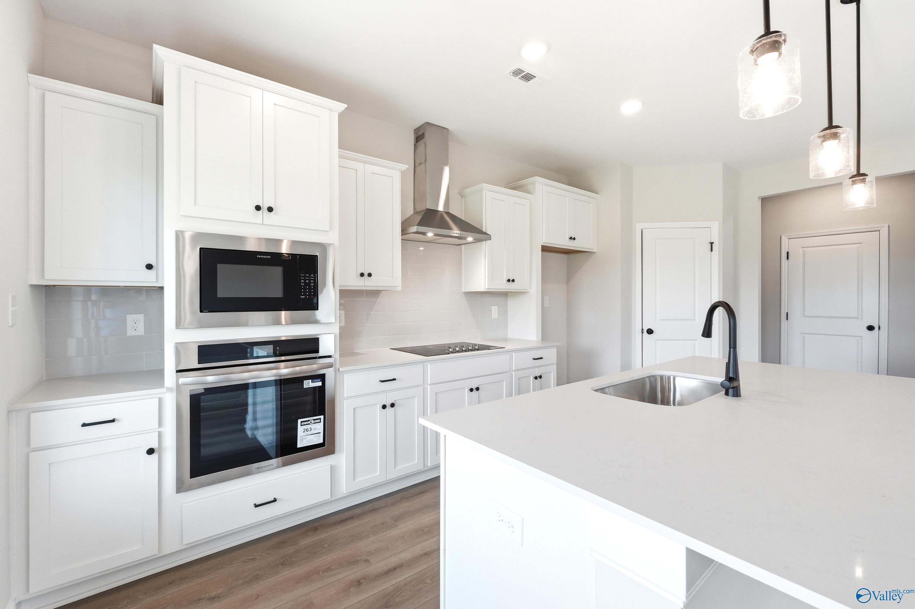Modern kitchen with white cabinets, stainless steel appliances, and large island in The Burton B at Heritage Lakes.
