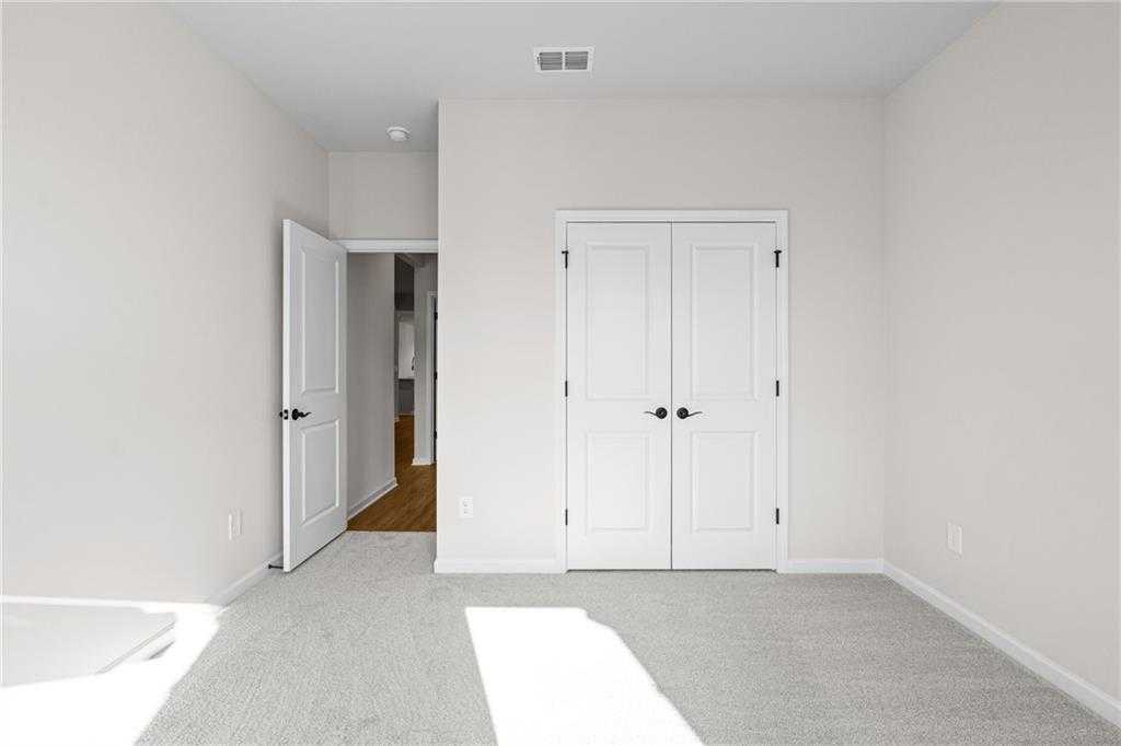 Spacious master bedroom with white double closet doors and open hallway entry in Davidson Homes The Edison A, Loganville, GA