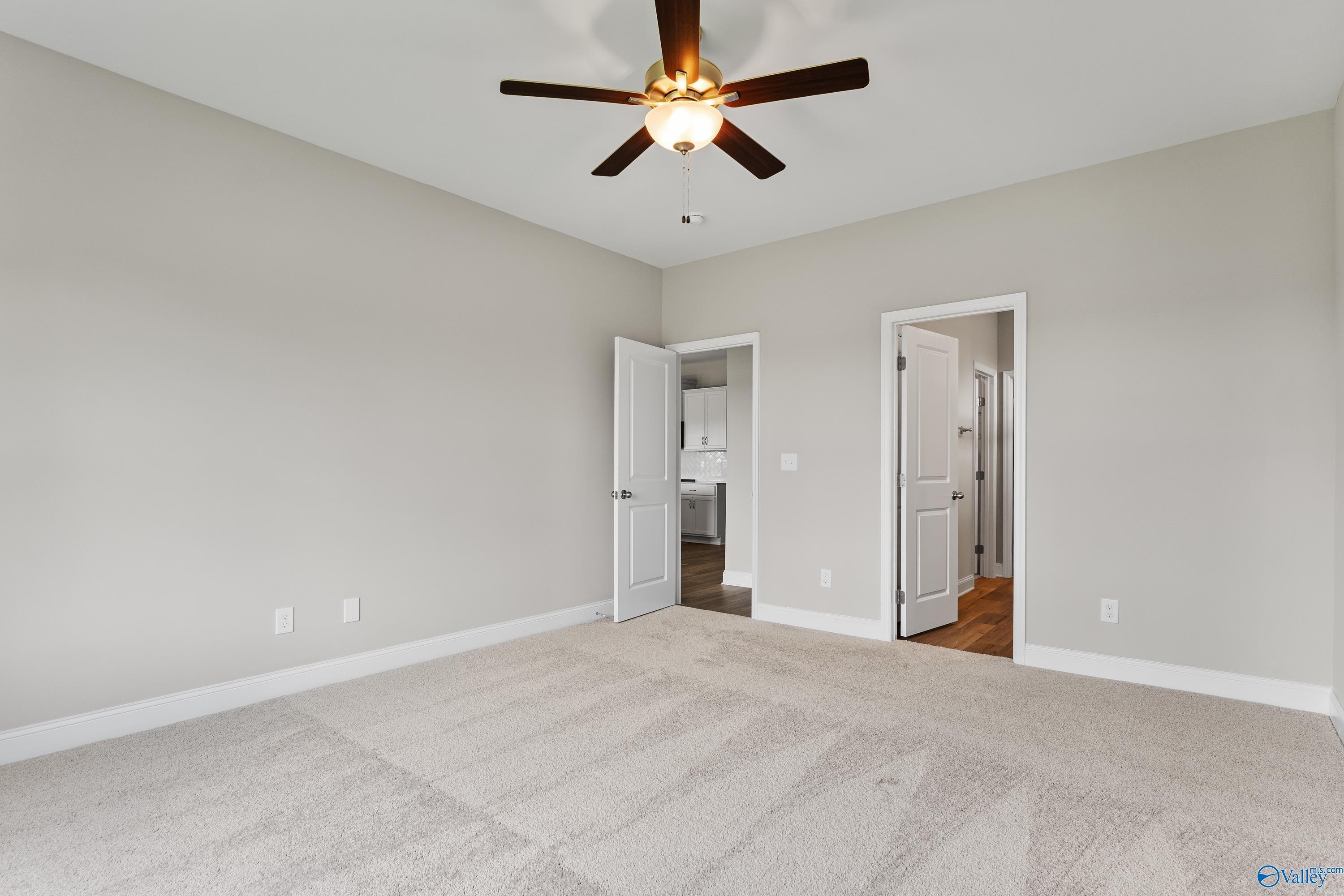 Spacious bedroom with ceiling fan, en-suite bath access, and neutral tones in Davidson Homes The Daphne C, Harvest, Alabama