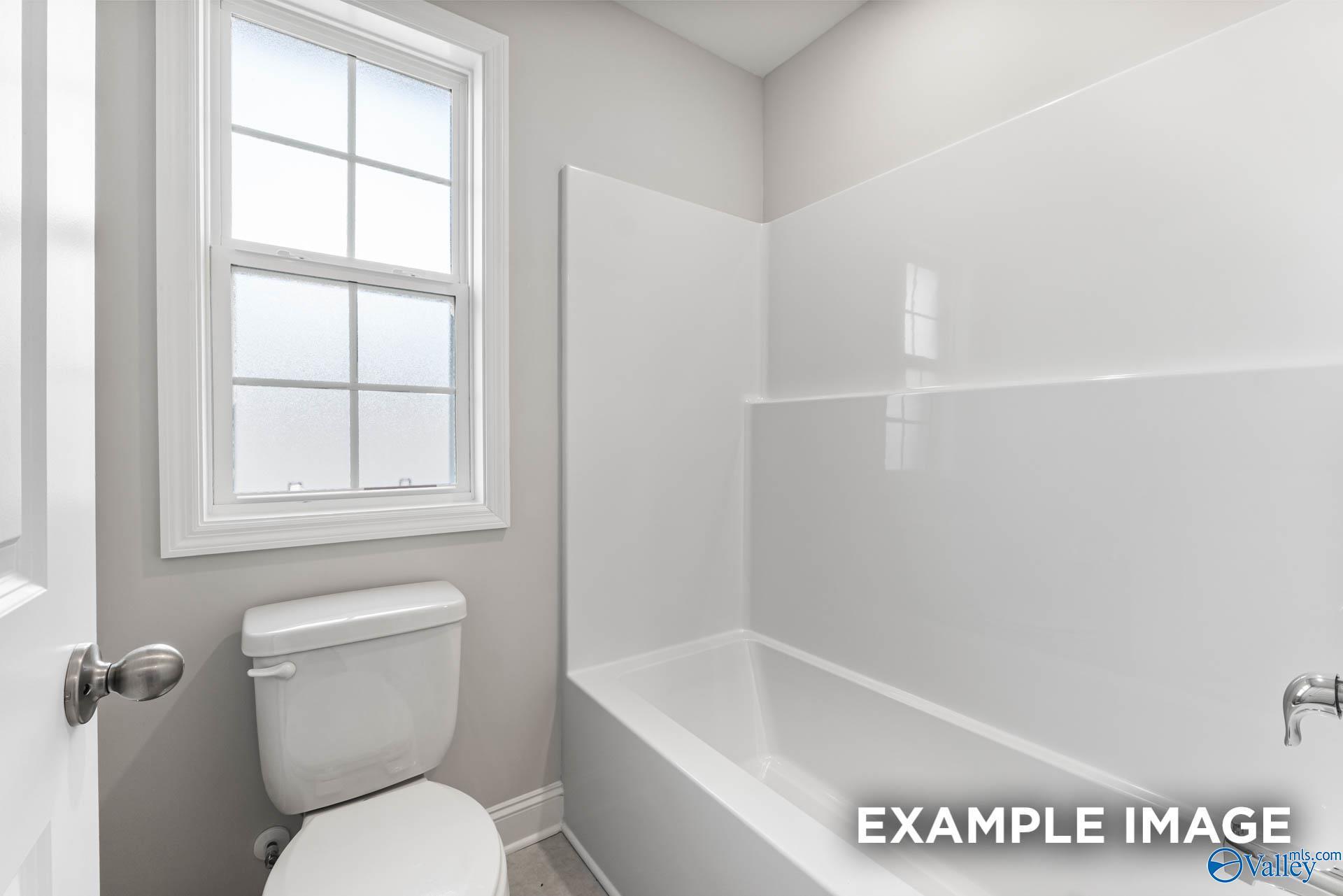 Modern white bathtub and shower combo with toilet in Davidson Homes The Madison A, Meridianville, Alabama