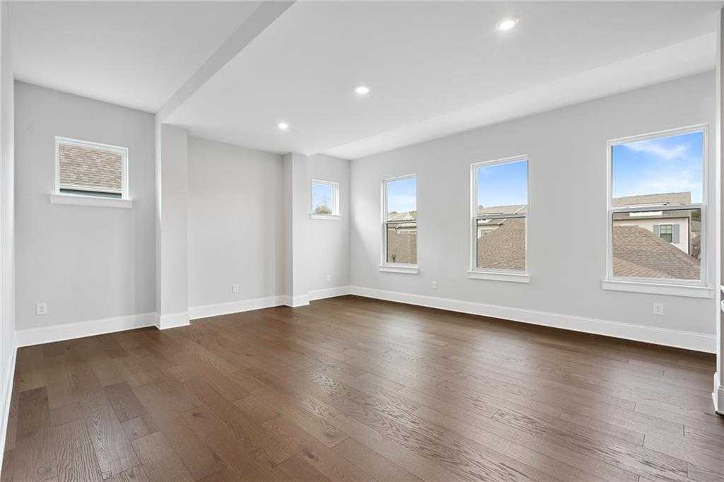 Spacious empty living room with light gray walls, dark hardwood floors, and large windows in Davidson Homes The Seaside B, Woodstock, GA