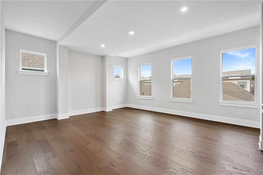 Spacious empty living room with light gray walls, dark hardwood floors, and large windows in Davidson Homes The Seaside B, Woodstock, GA