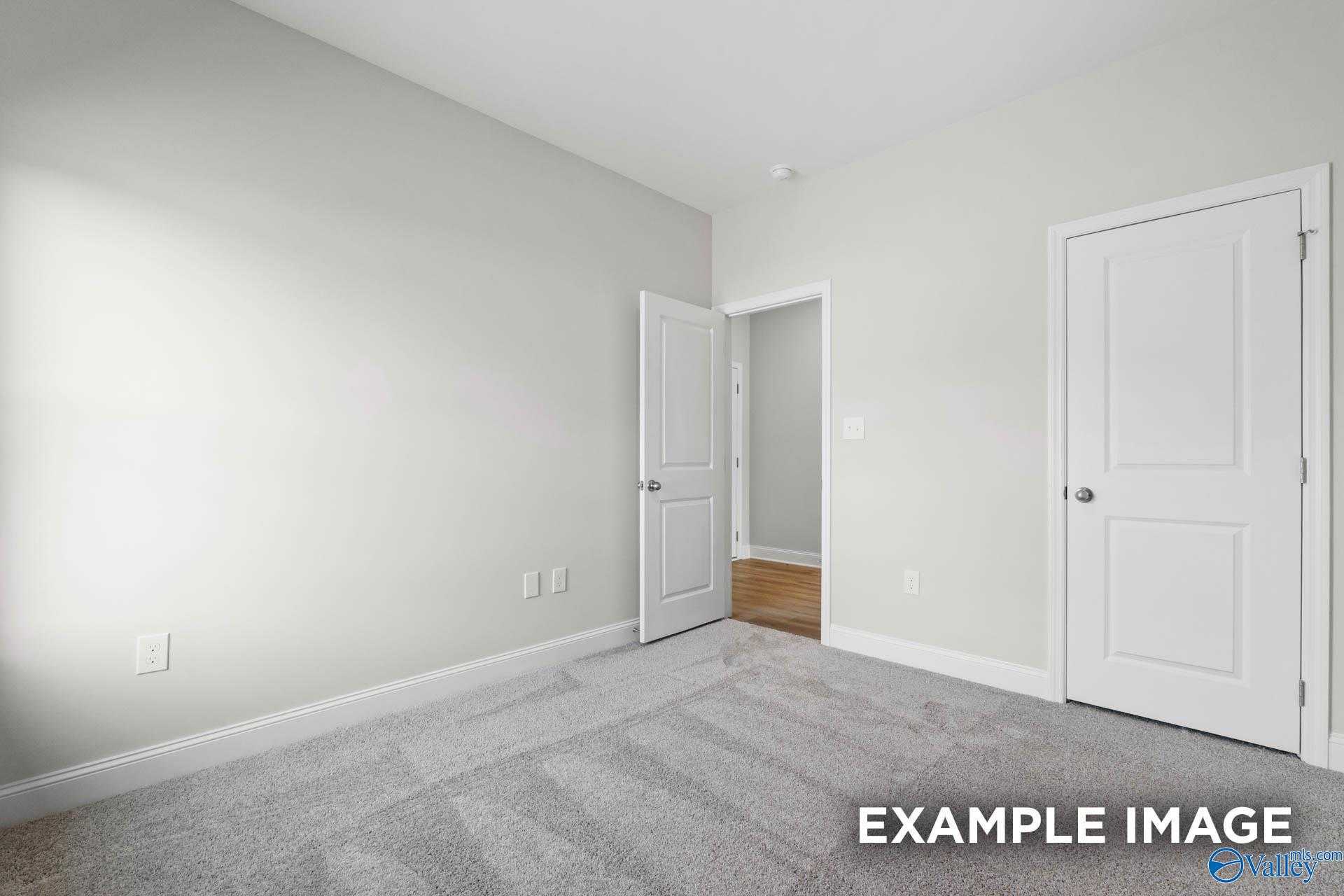 Neutral bedroom with light gray walls, white doors, and plush carpet in Davidson Homes The Butler, Huntsville, AL