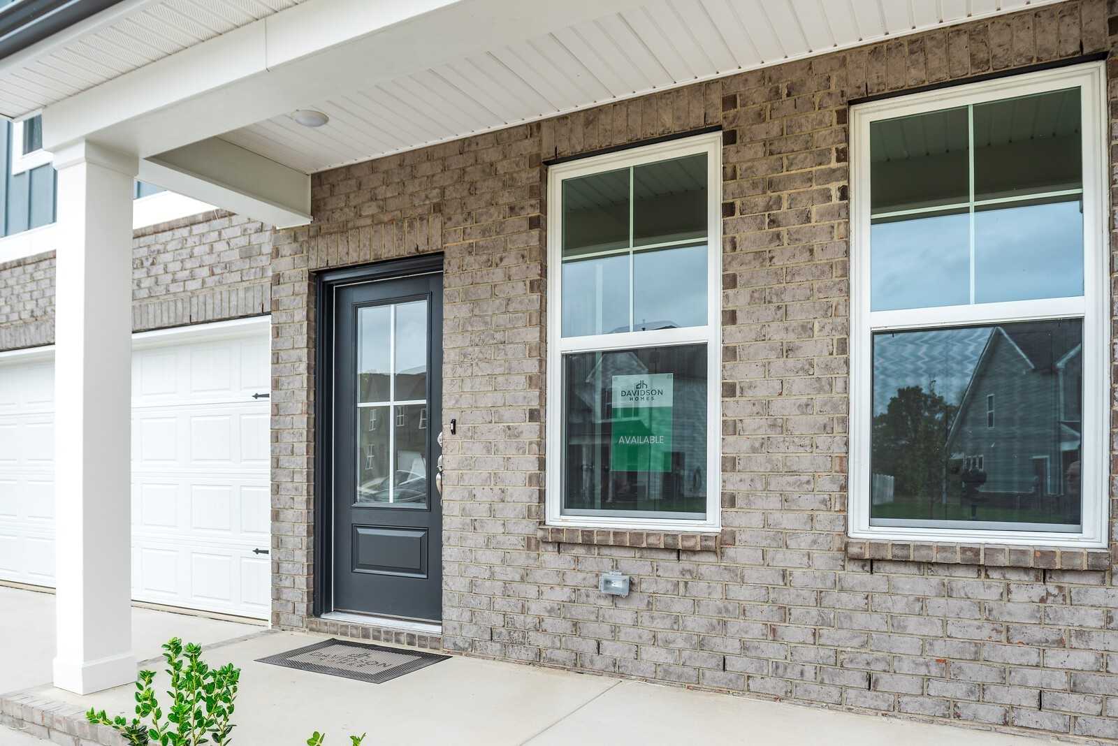 Modern brick two-story home exterior with covered porch, black door, large windows, and 2-car garage in Davidson Homes The Logan C, Gallatin, TN