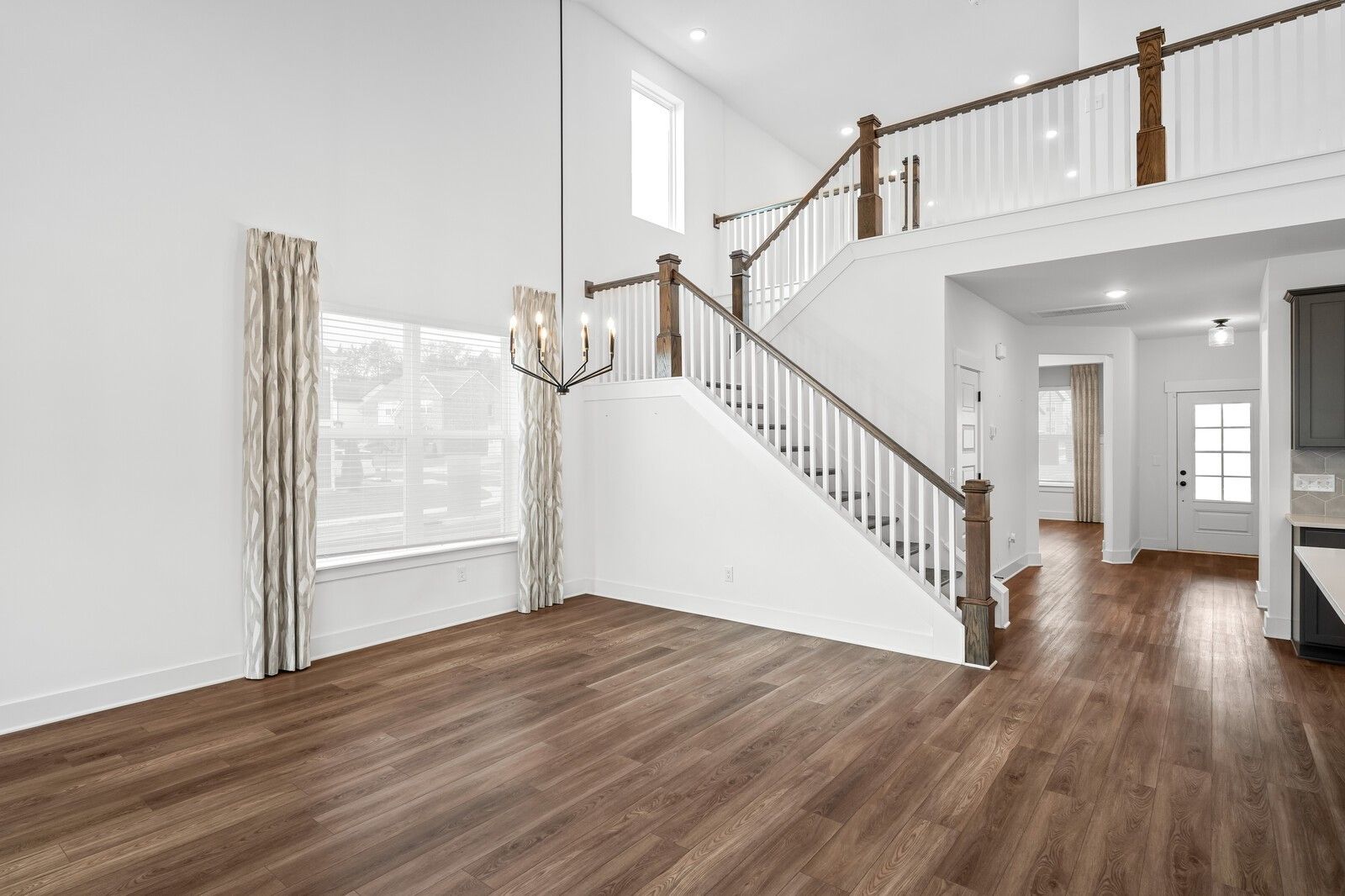 Grand two-story foyer with wooden staircase, chandelier, and large curtained windows in Davidson Homes The Ridgeport, Gallatin, TN