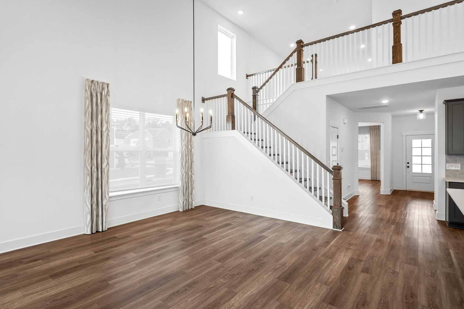 Grand two-story foyer with wooden staircase, chandelier, and large curtained windows in Davidson Homes The Ridgeport, Gallatin, TN