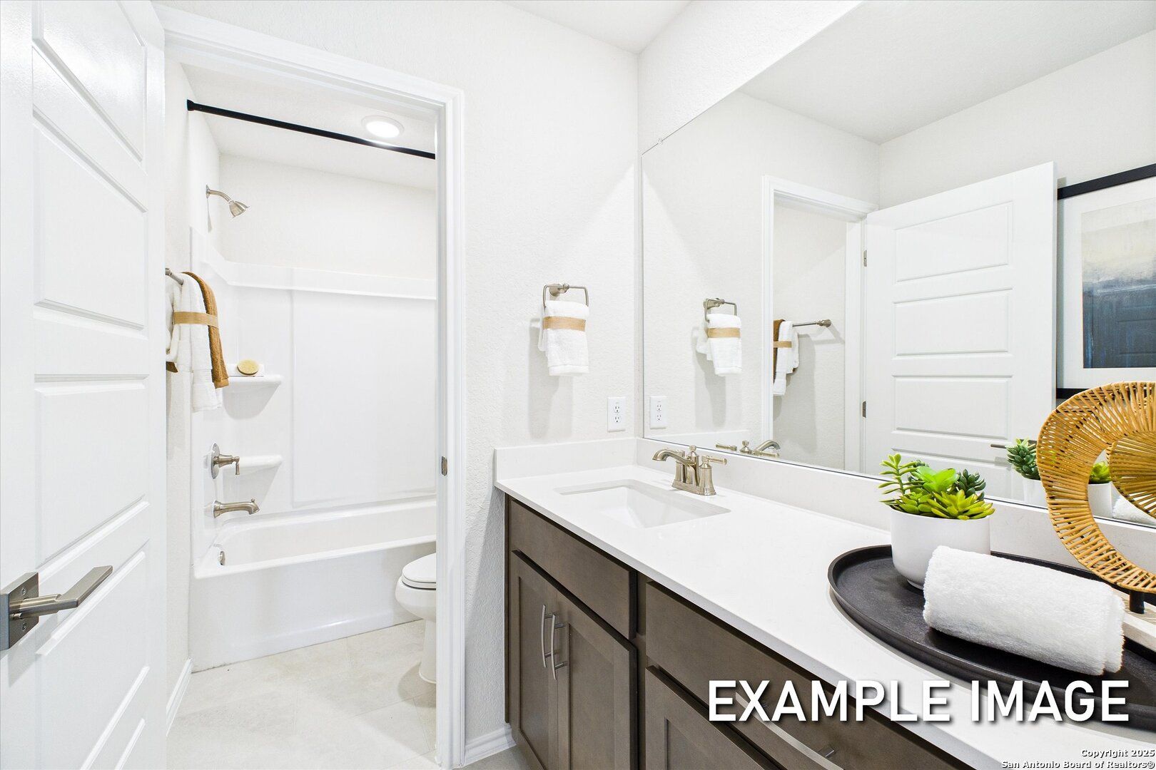 Modern white bathroom with deep soaking tub, walk-in shower, dual-sink vanity, and mirrored wall in Davidson Homes The Brazos C, San Antonio