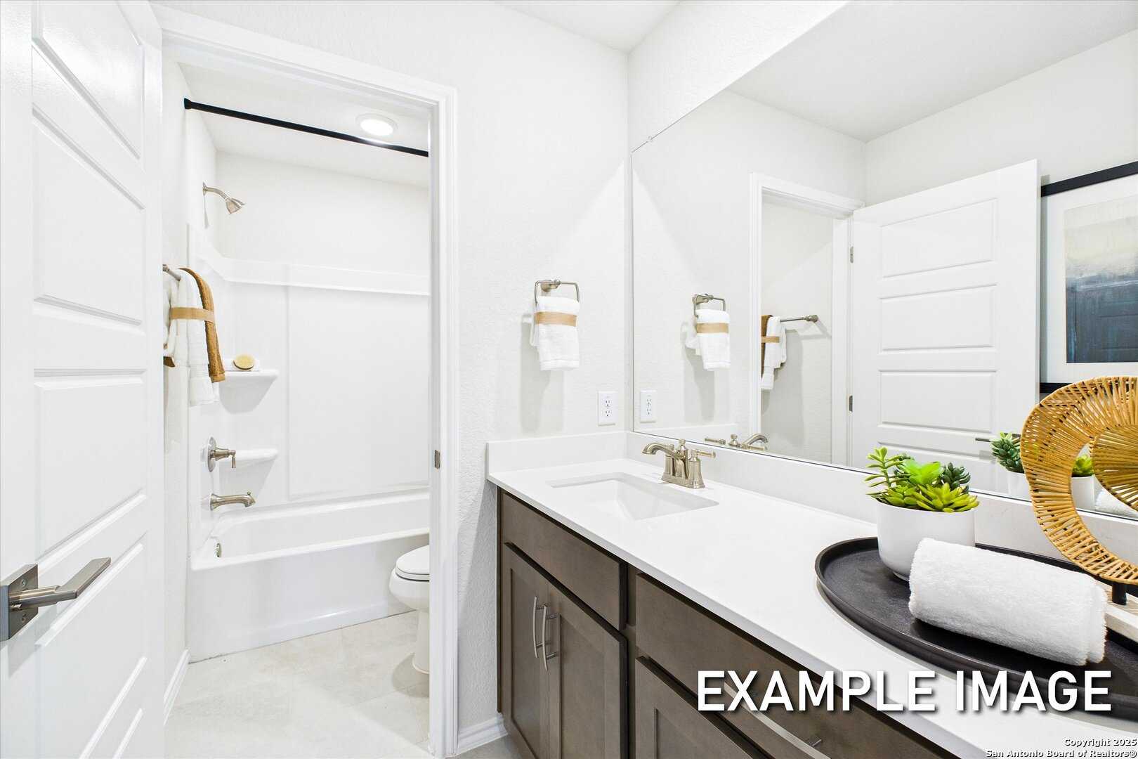 Bright bathroom with glass shower, soaking tub, quartz vanity, and large mirror in 5-bedroom Davidson Homes The Brazos C, San Antonio, Texas