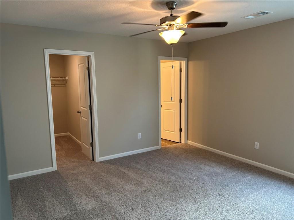 Spacious secondary bedroom with ceiling fan, beige walls, gray carpet, closet, and bath access in Davidson Homes The Washington, Phenix City