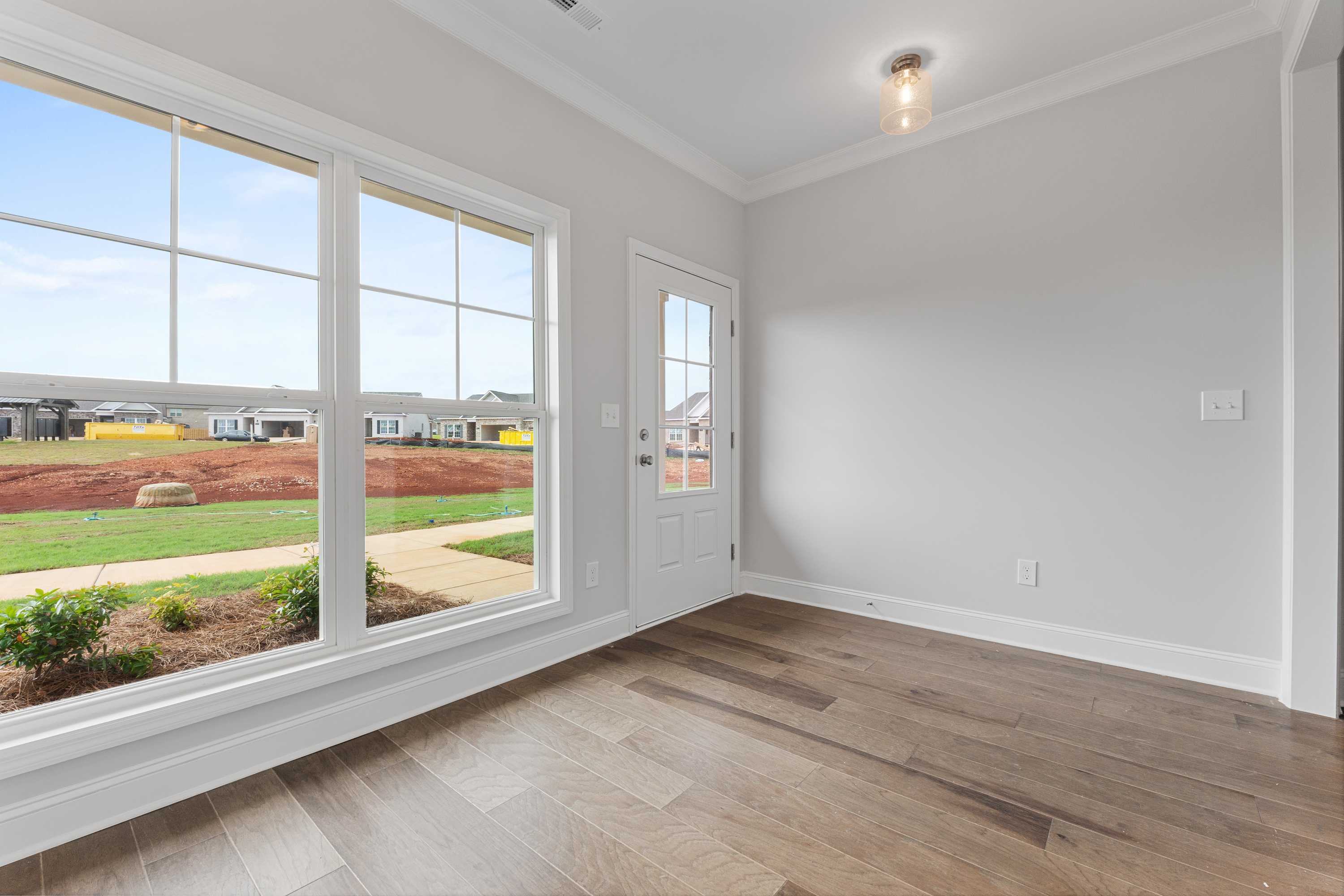 Spacious home study with large windows overlooking new construction at The Villas at Barnett's Crossing in Madison, Alabama, hardwood floors, gray walls