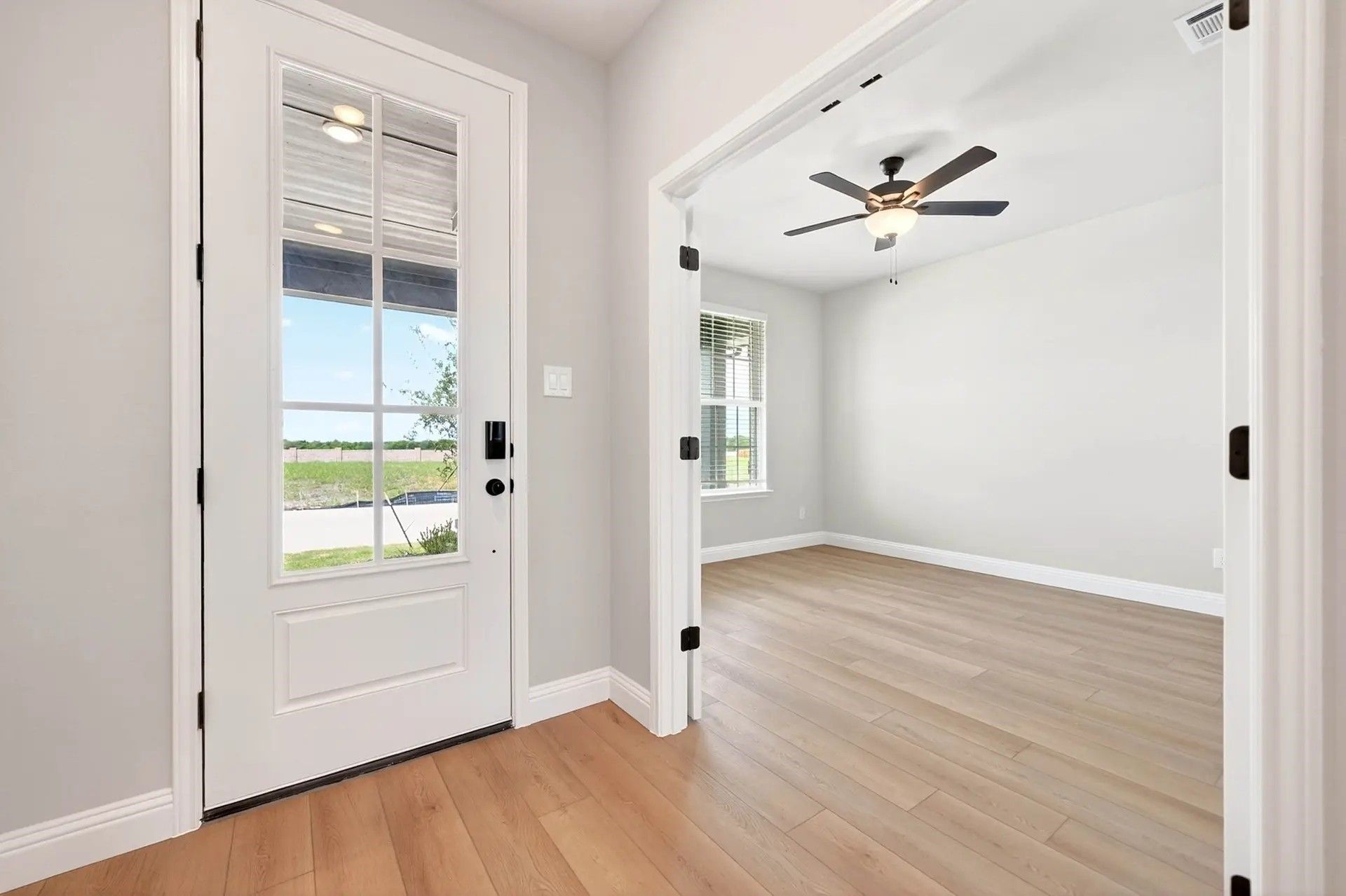 Bright entryway with glass-paneled front door and view of flex room in The Holly C floor plan by Davidson Homes in Heartland.