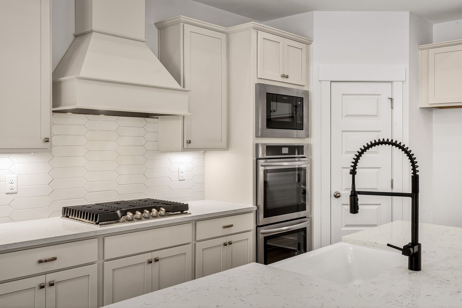 Modern white kitchen with shaker cabinets, quartz counters, gas range, double ovens, subway tile backsplash, and black faucet in Ridgeport C home, Gallatin, TN
