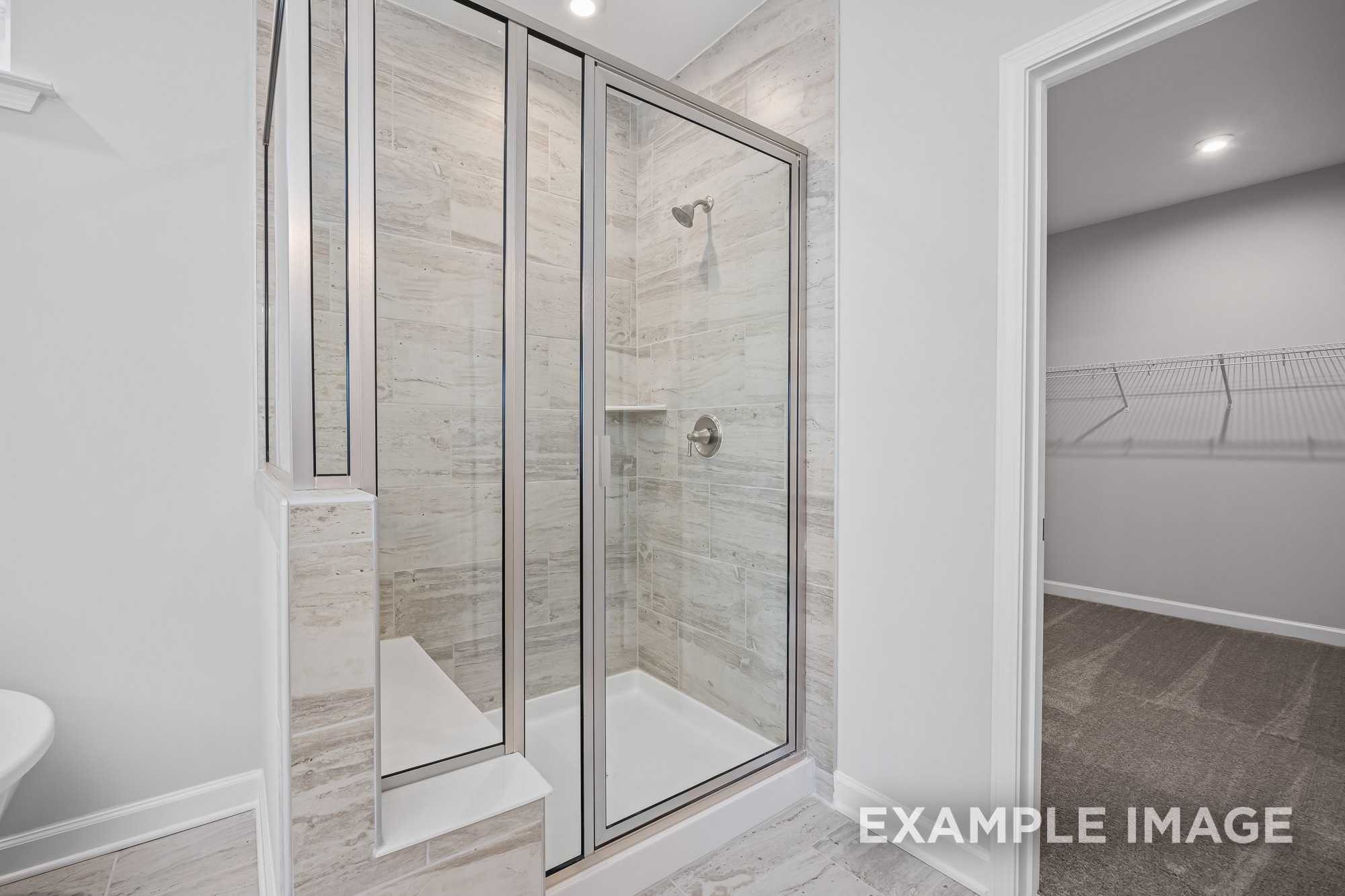 Modern master bathroom in The Cypress D II featuring frameless glass shower, subway tile, and walk-in closet