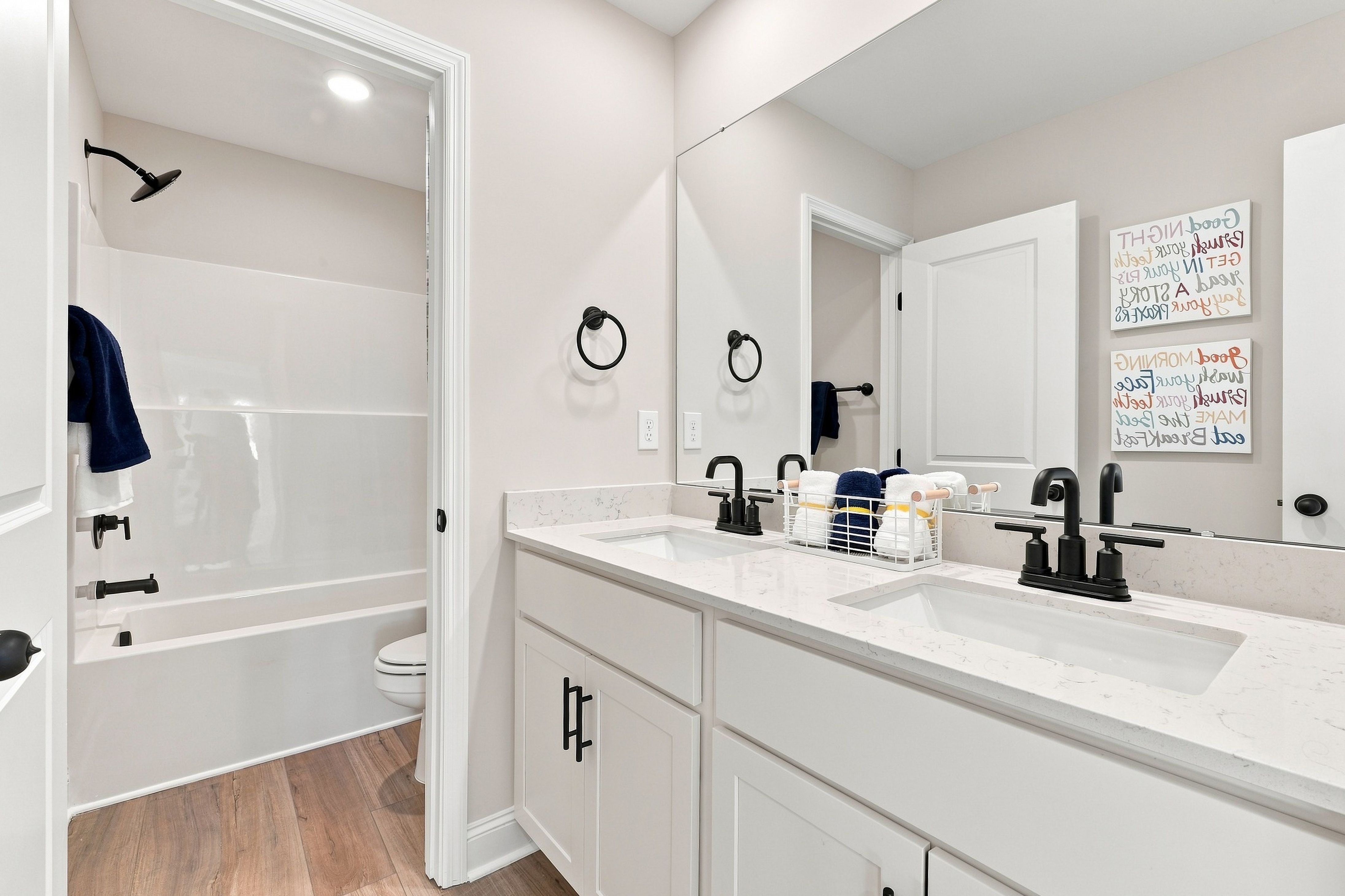 Dual vanity bathroom with white cabinetry, black matte faucets, and tub shower at Bailey Park by Davidson Homes in Fayetteville, TN