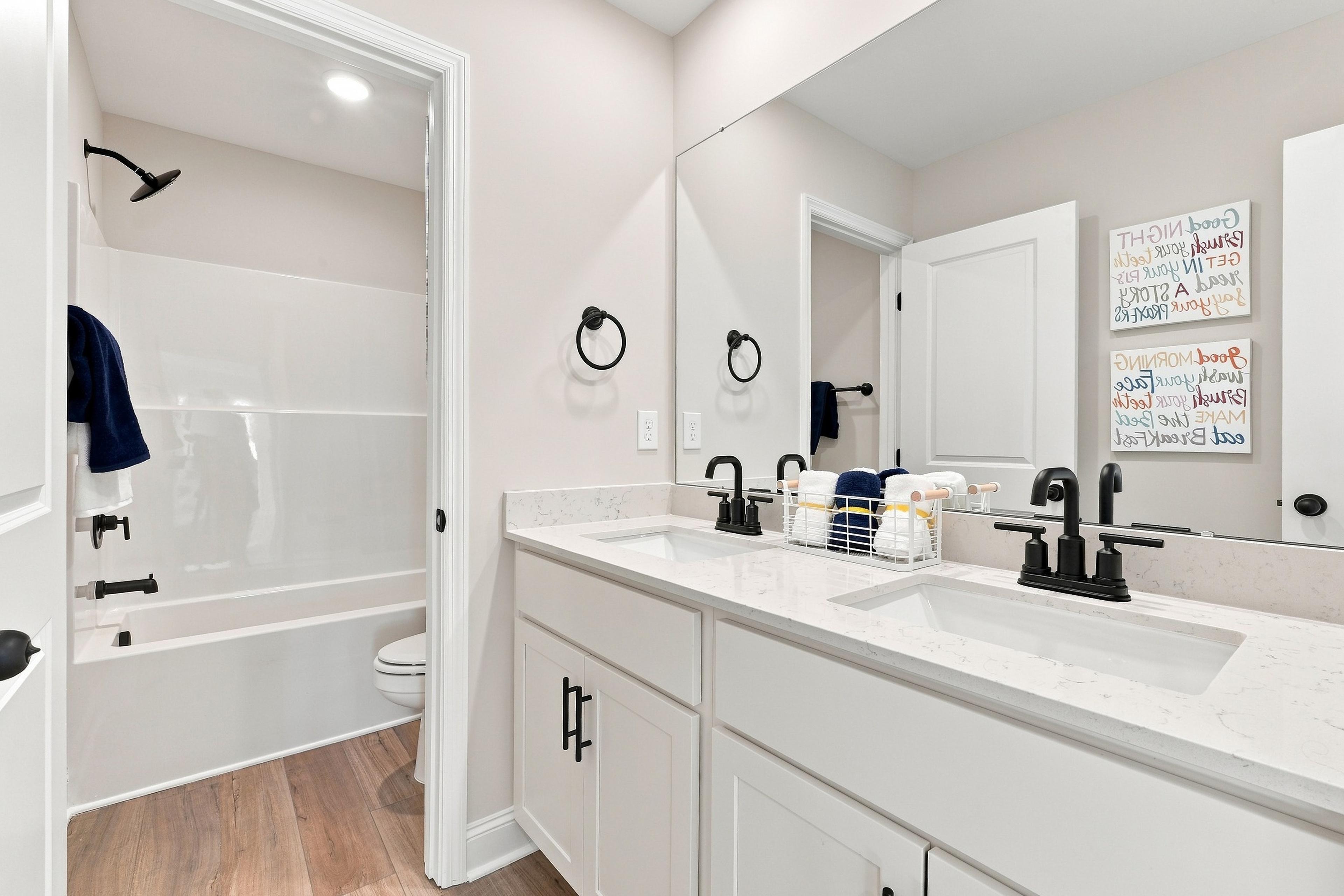 Dual vanity bathroom with white cabinetry, black matte faucets, and tub shower at Bailey Park by Davidson Homes in Fayetteville, TN