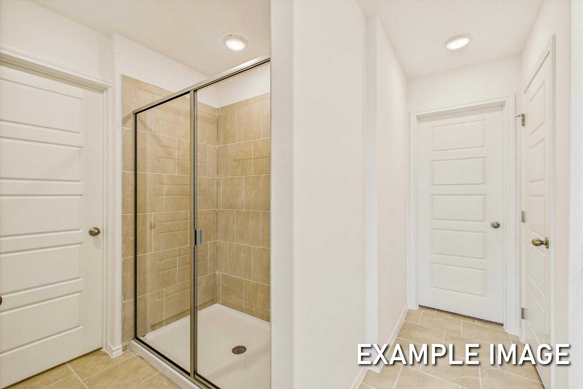 Modern master bathroom in The Trinity B showcasing walk-in shower with glass enclosure and beige tile walls
