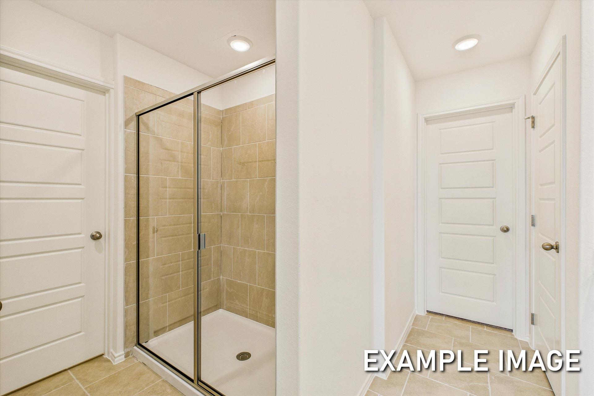 Modern master bathroom in The Trinity B showcasing walk-in shower with glass enclosure and beige tile walls