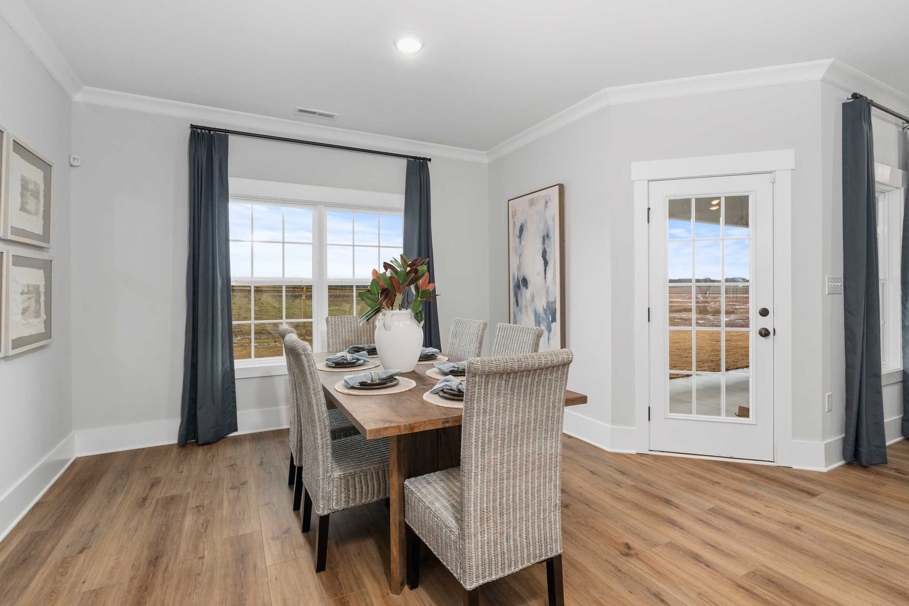 Elegant dining room at Kendall Farms in Toney, Alabama with wooden table, upholstered chairs, floral vase, and large window views