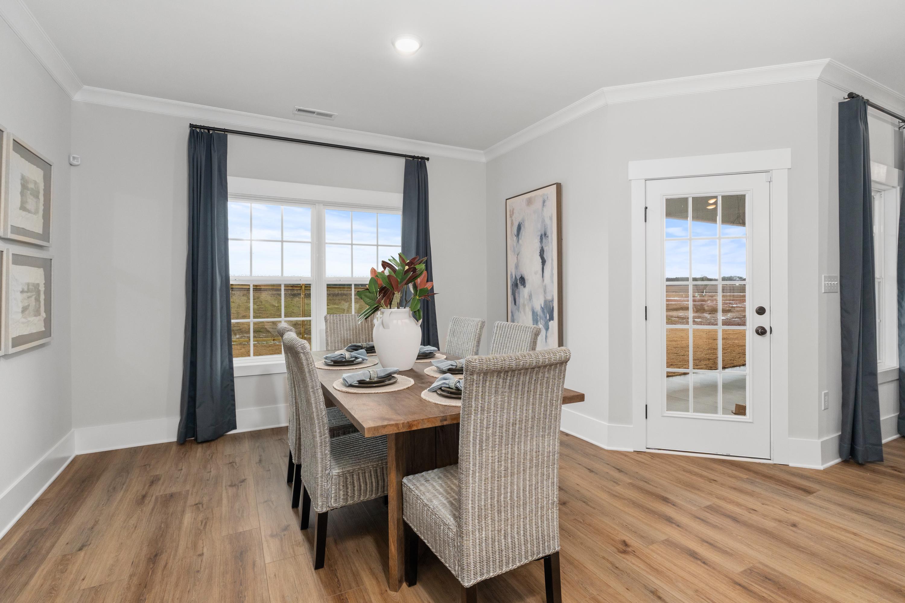 Elegant dining room at Kendall Farms in Toney, Alabama with wooden table, upholstered chairs, floral vase, and large window views