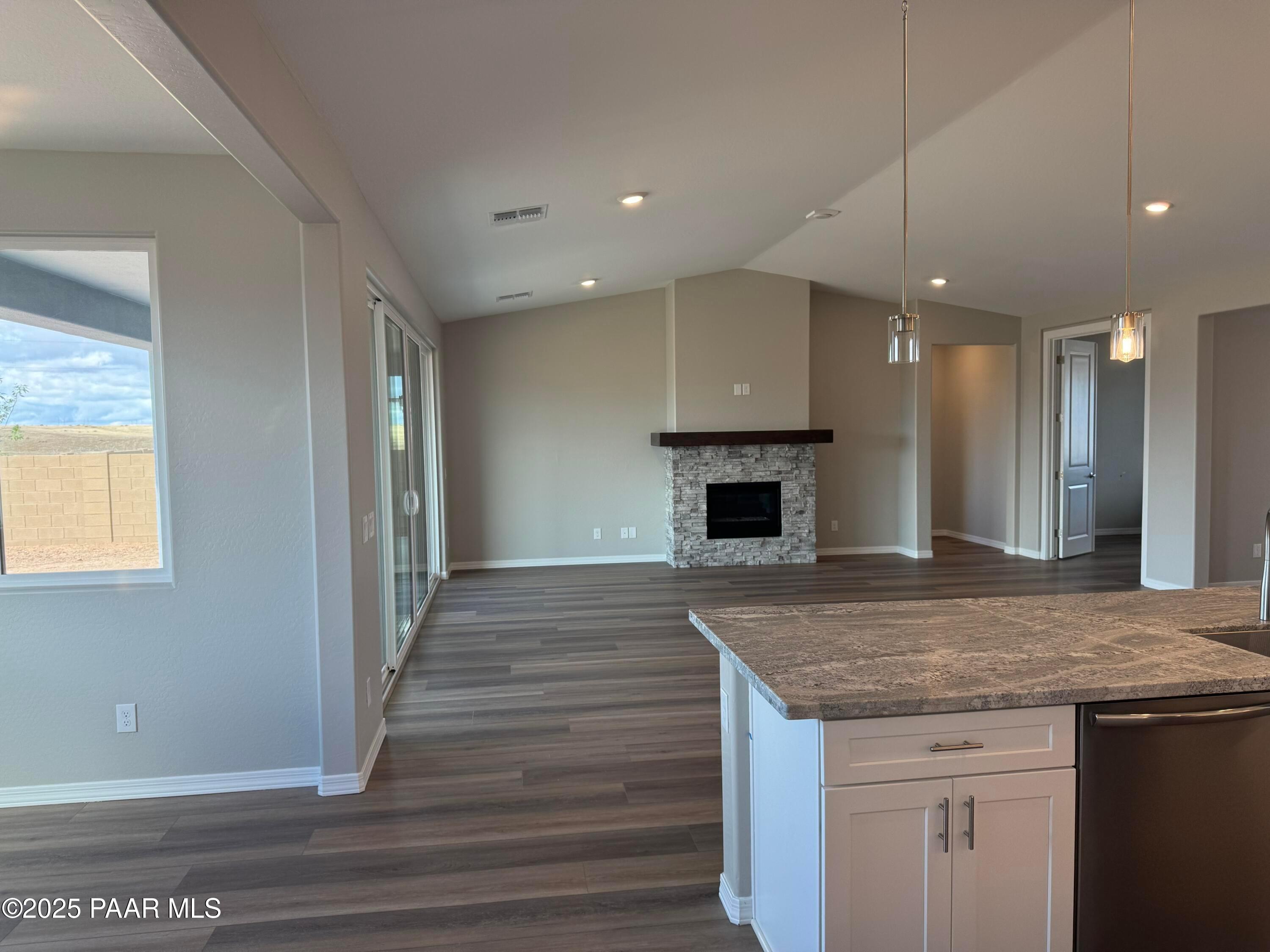 Open-concept living room with stone fireplace, kitchen island, and desert views in Davidson Homes The Monarch A, Prescott AZ