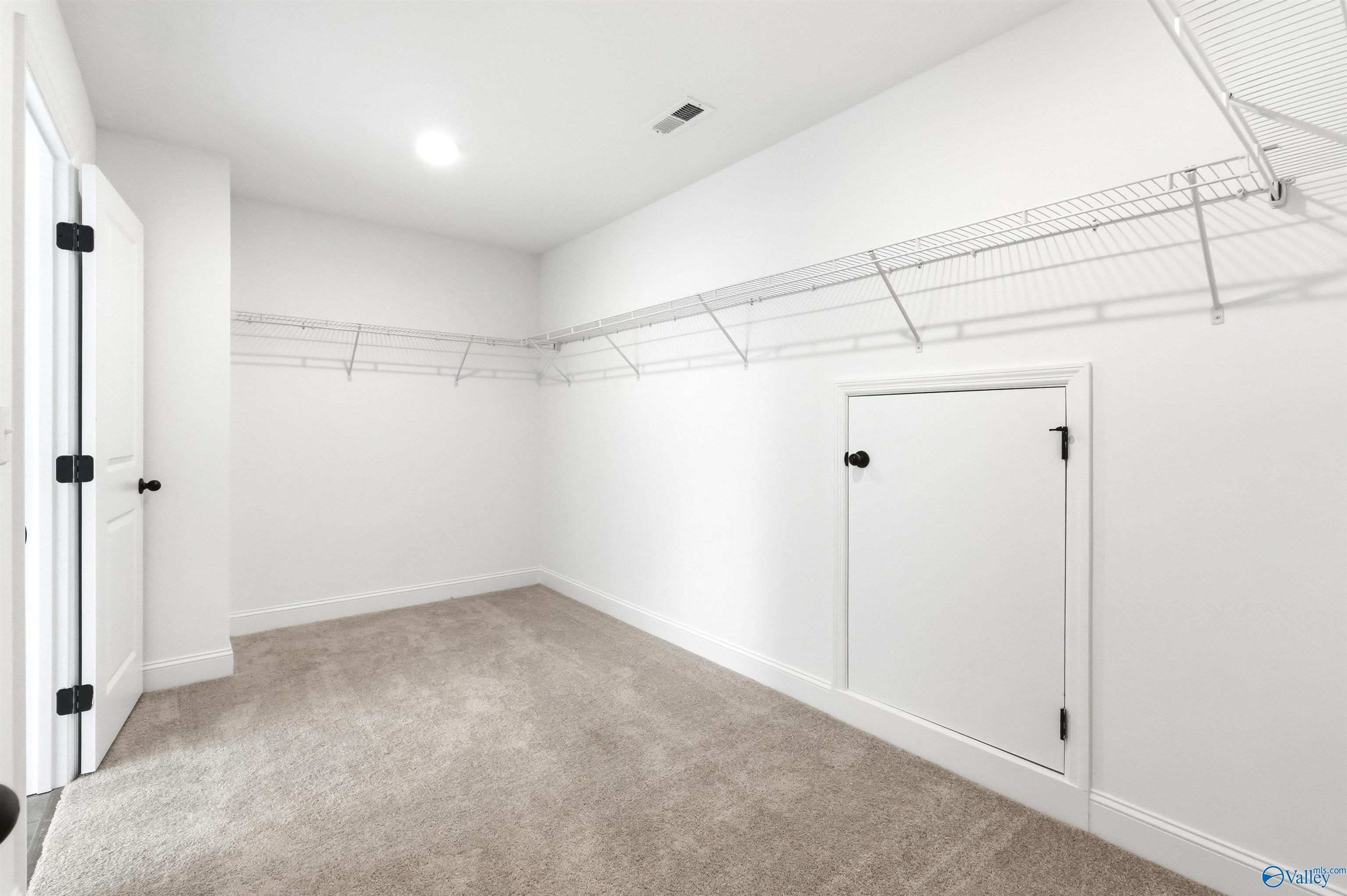 Walk-in closet with wire shelving and attic access door in The Chelsea D floor plan at Berry Cove in New Market, AL.