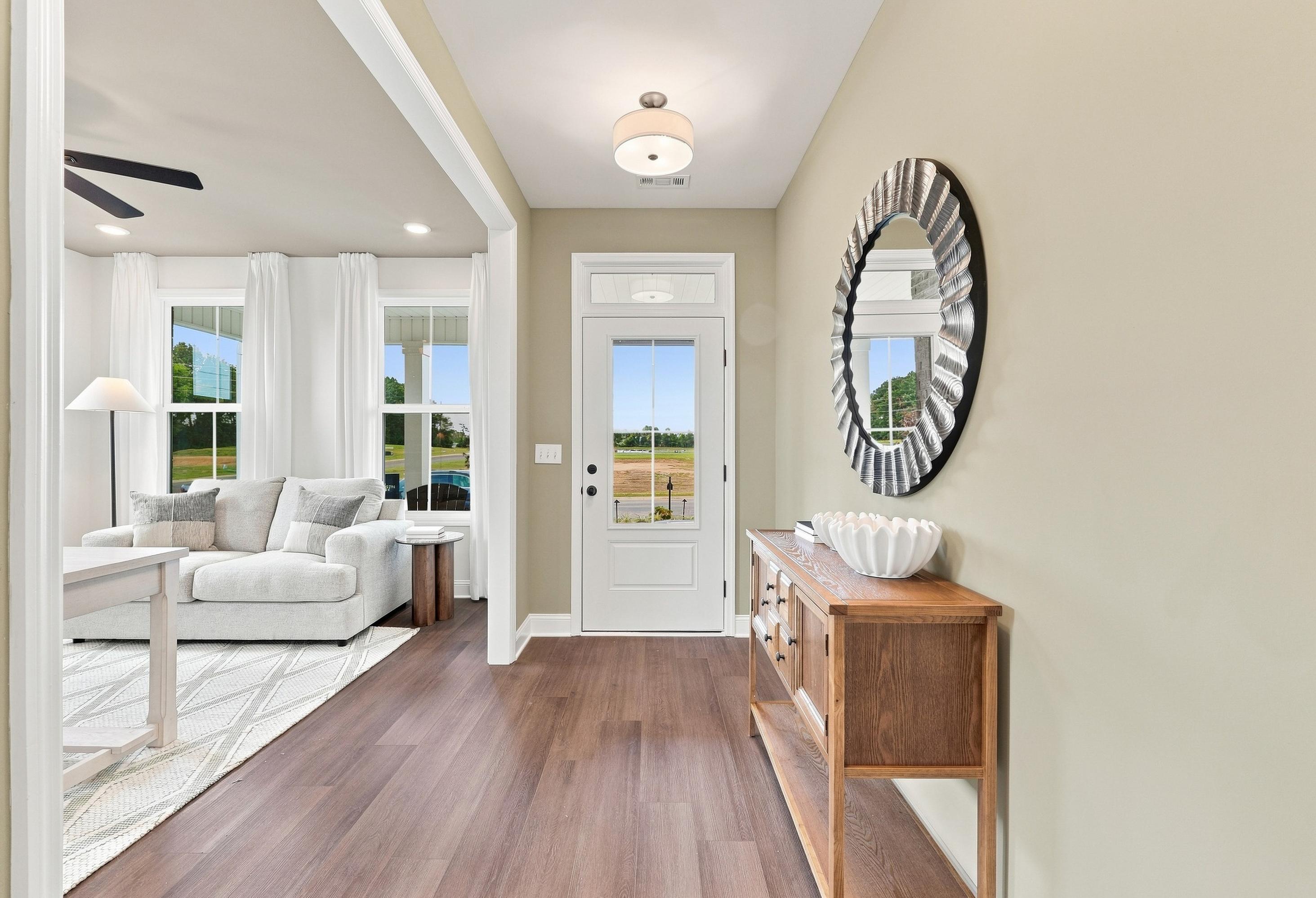 Welcoming foyer and open-concept living area in The Ashport by Davidson Homes, featuring wood floors and modern decor.