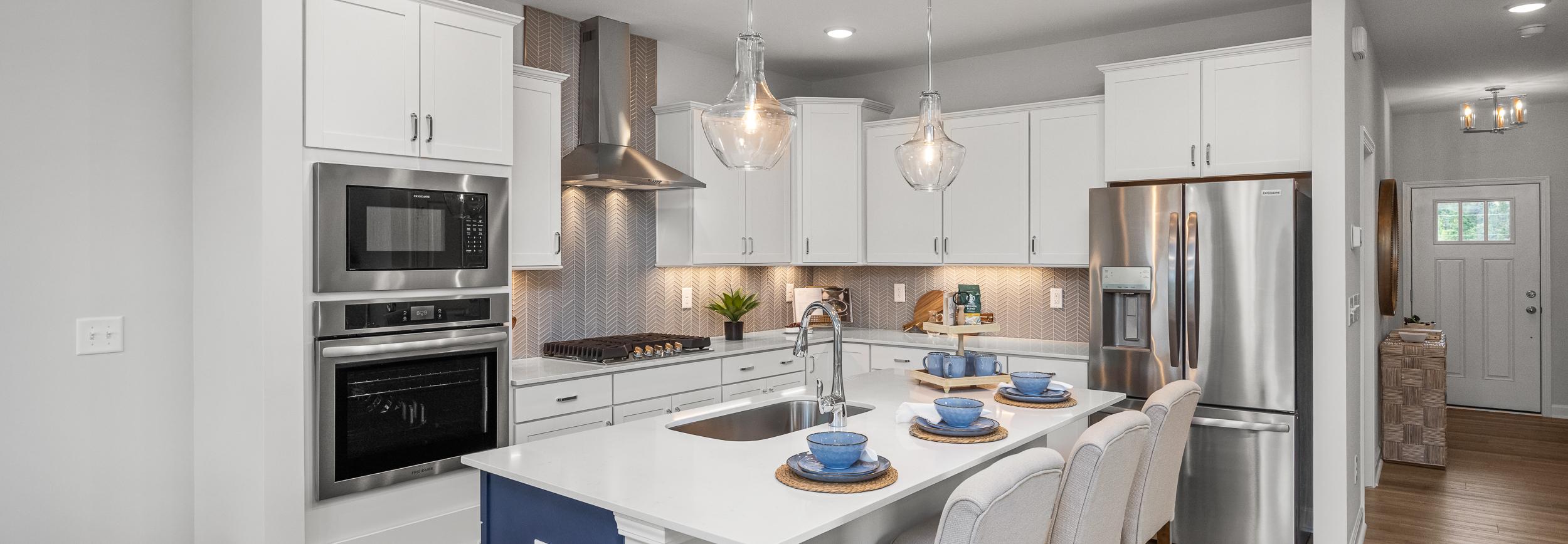 Spacious modern kitchen in Summers Walk Davidson NC with white cabinetry island seating stainless appliances hardwood floors